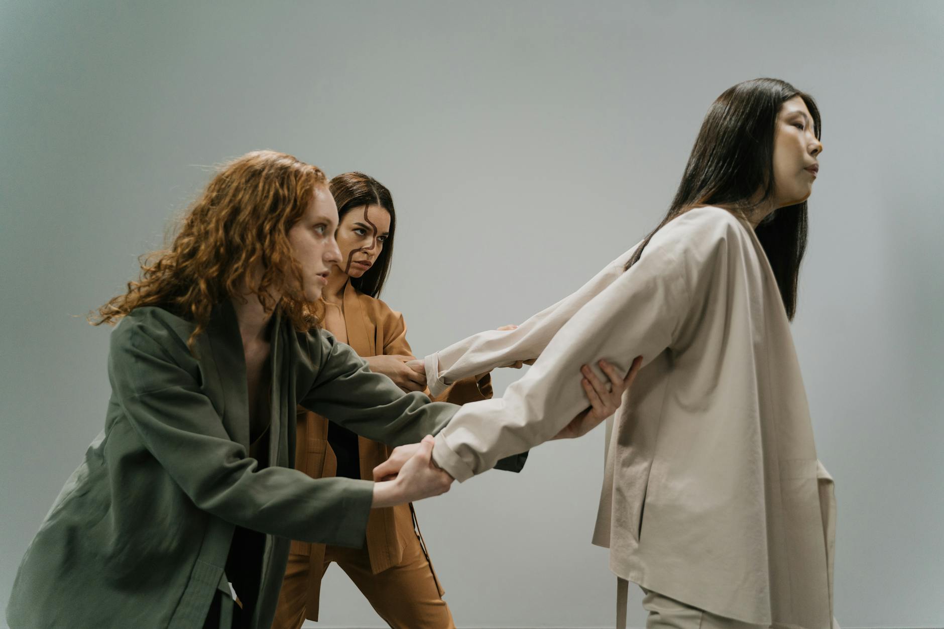 Three women in a conceptual studio shoot conveying struggle and connection. - release relationship resentments