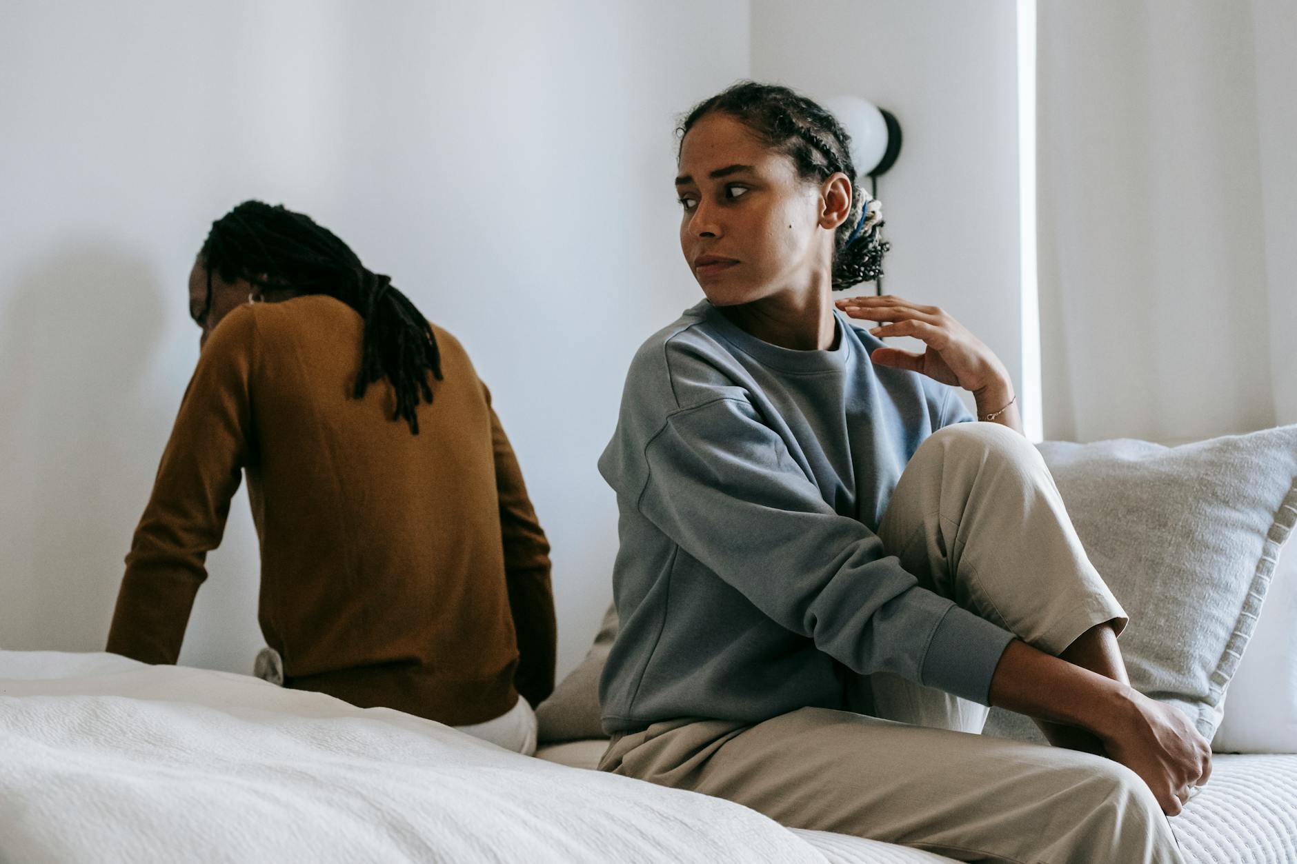 Young African American couple wearing casual outfit sitting on different sides of bed with sad face at home in day - release relationship resentments