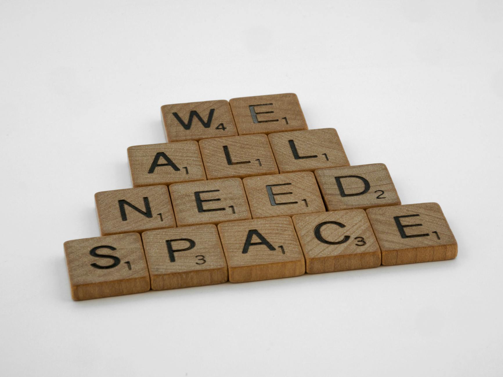 Creative arrangement of wooden letter tiles spelling 'We All Need Space' on a white background. - renovation communication needs