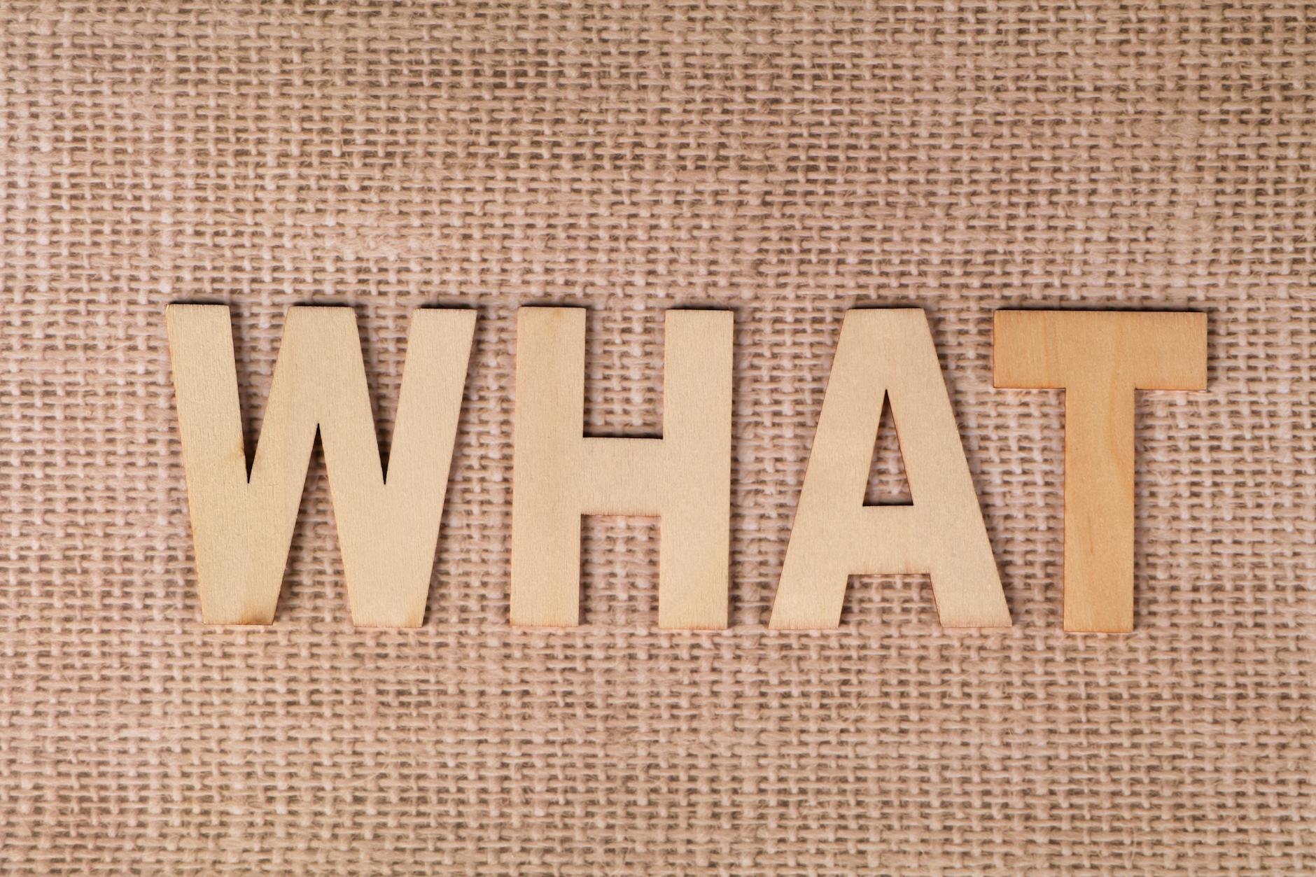 Wooden letters forming the word WHAT set on a textured burlap surface. - what is a resolution