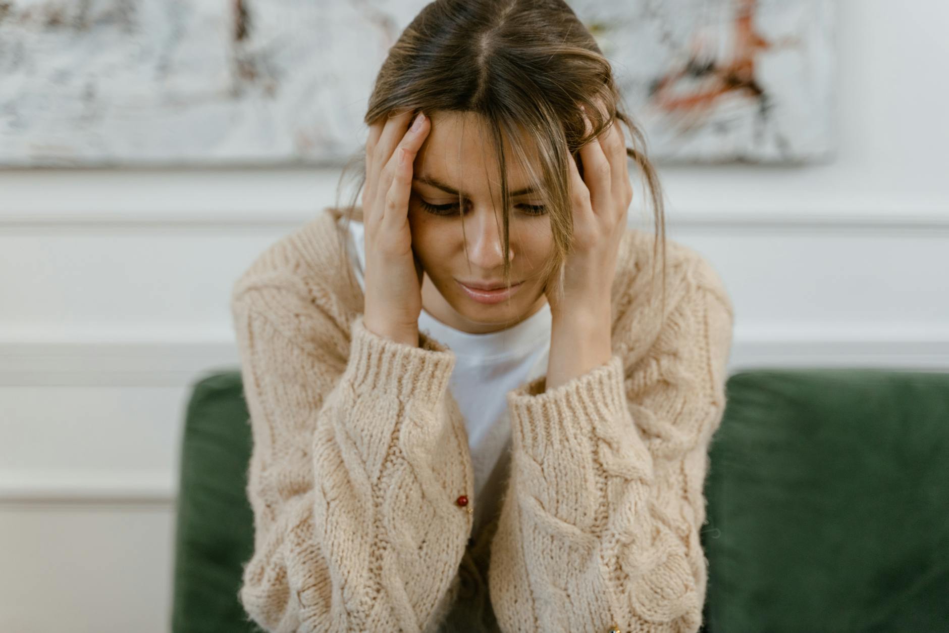 A woman sitting on a sofa holding her head, expressing stress and frustration indoors. - sad treatment options