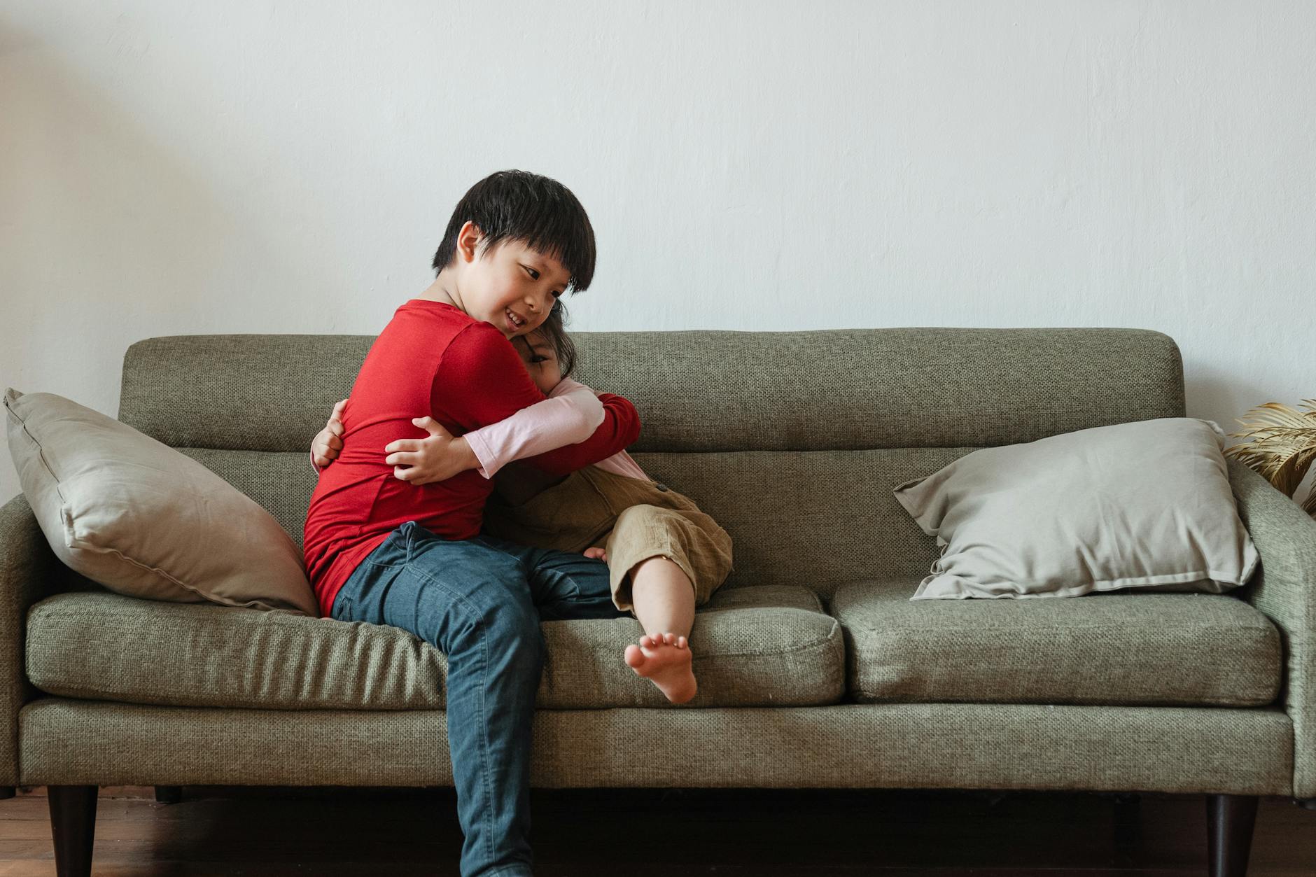 Two children sharing a heartfelt embrace on a cozy living room sofa, expressing love and joy. - sibling rivalry definition