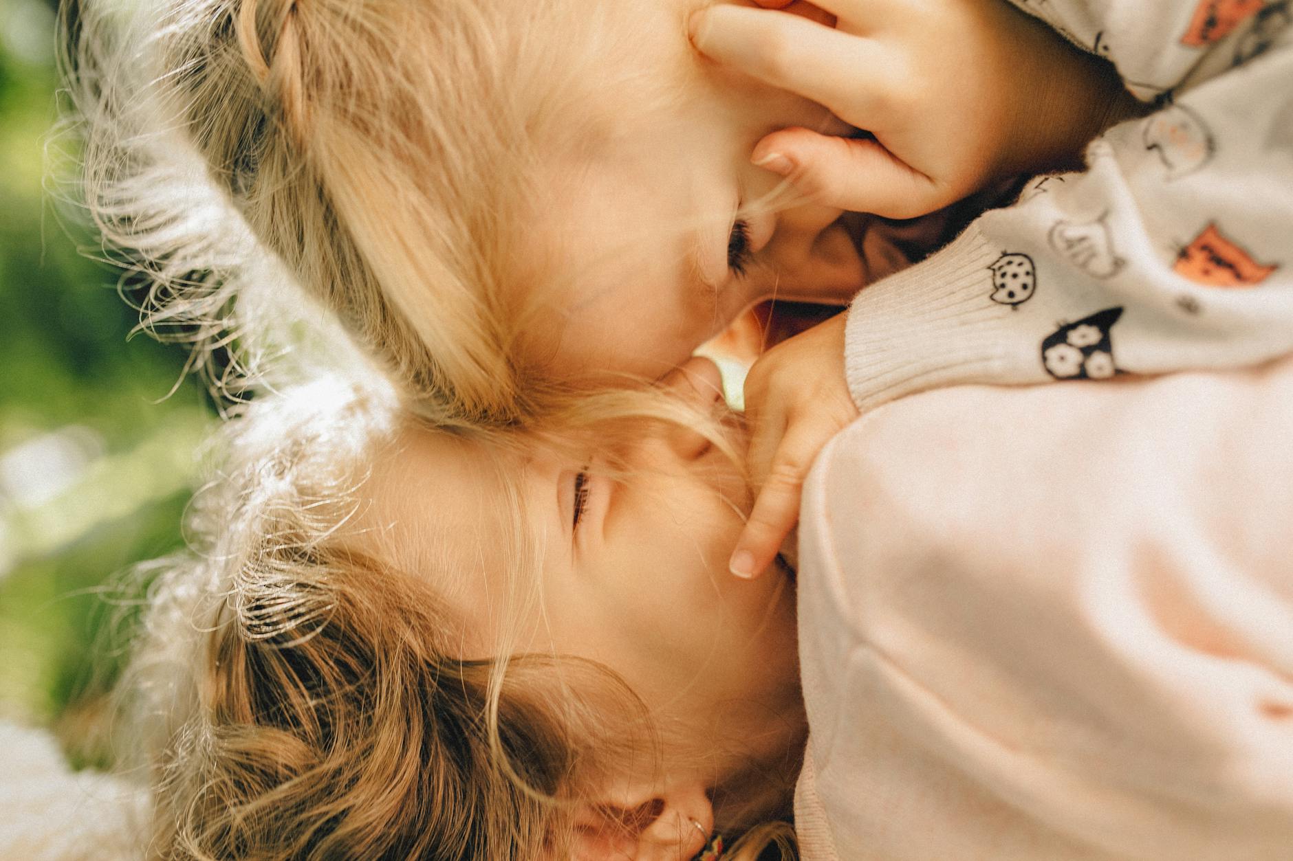 Heartwarming close-up of two blonde children playfully bonding outdoors. - sibling rivalry tips