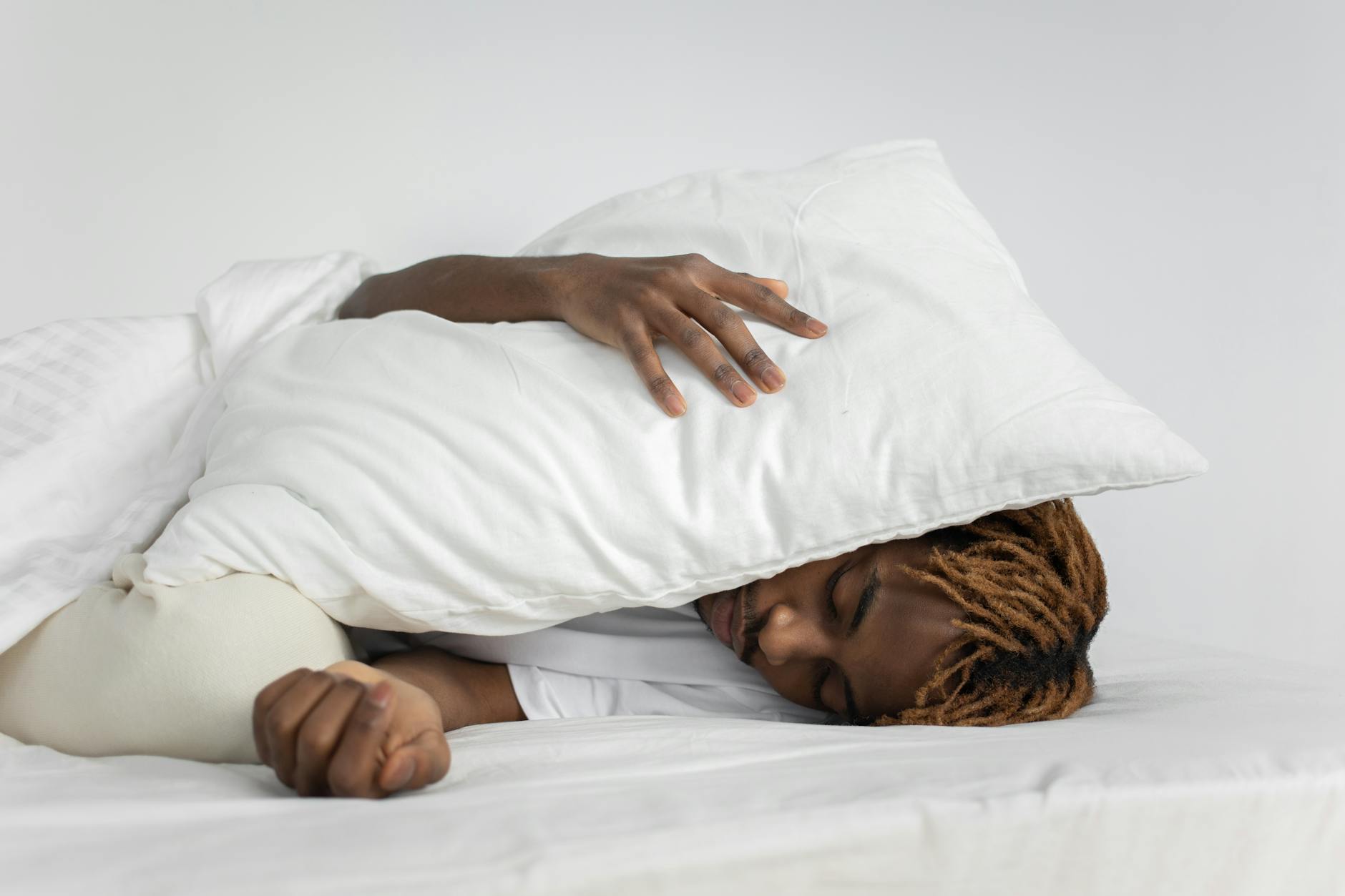 A person sleeping peacefully with a pillow covering their face, showcasing relaxation and rest. - sleep hygiene tips