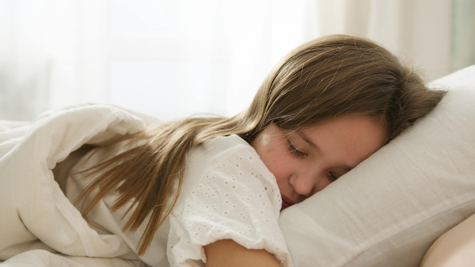 A young girl peacefully sleeping on a pillow, enveloped in soft light and comfort. - sleep hygiene tips
