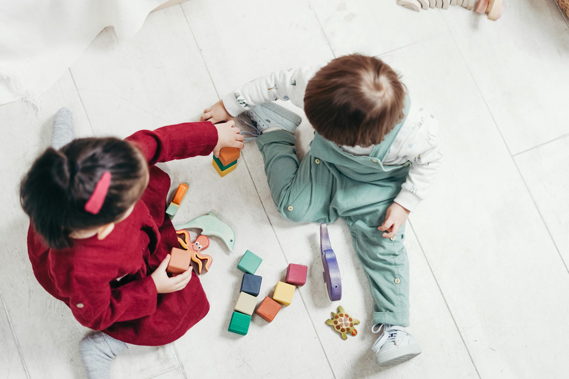 Two young children engaging with colorful wooden blocks indoors, fostering creativity and fun. - social skills playdates