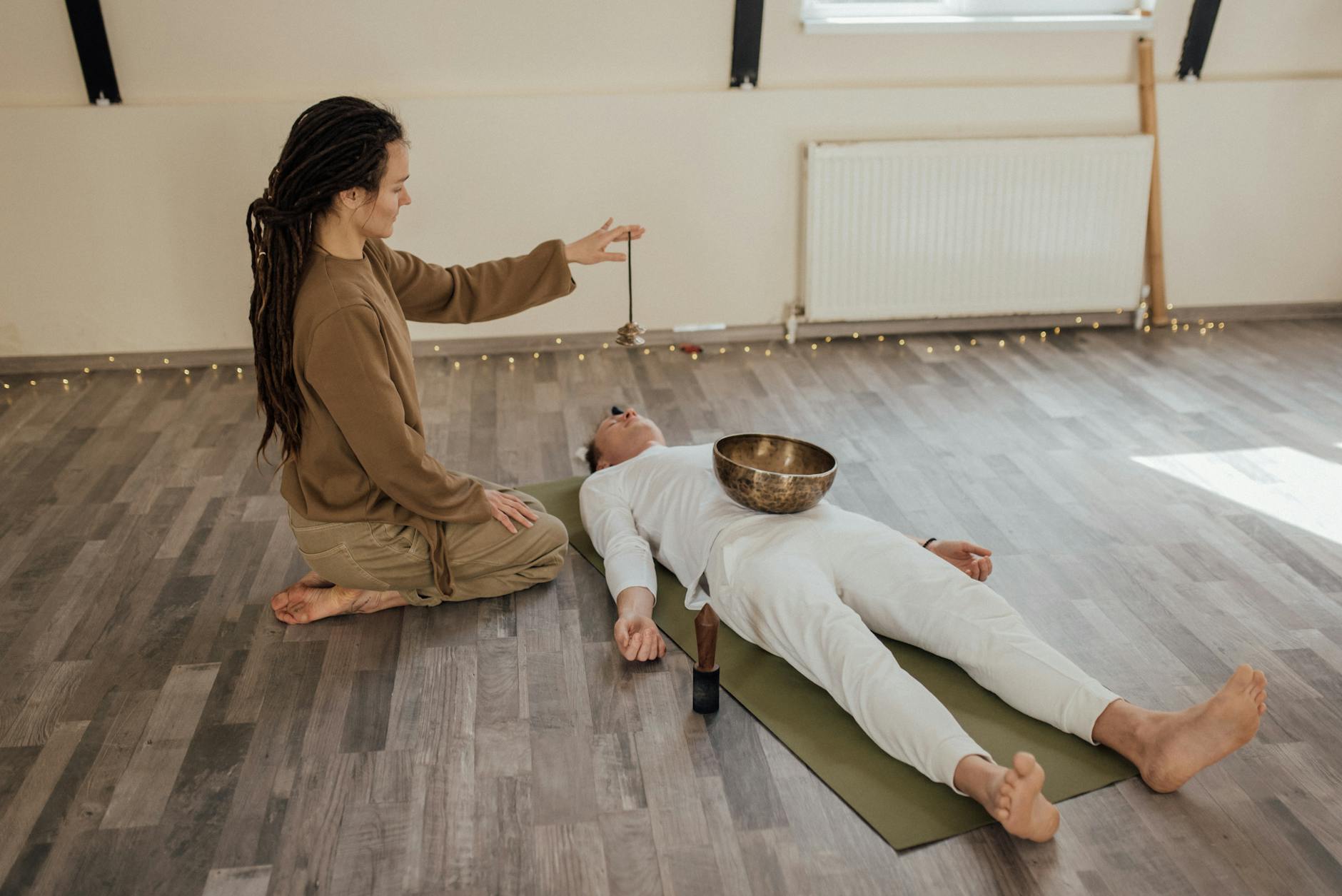 Two adults meditating indoors with a Tibetan singing bowl during a relaxation ritual. - somatic healing