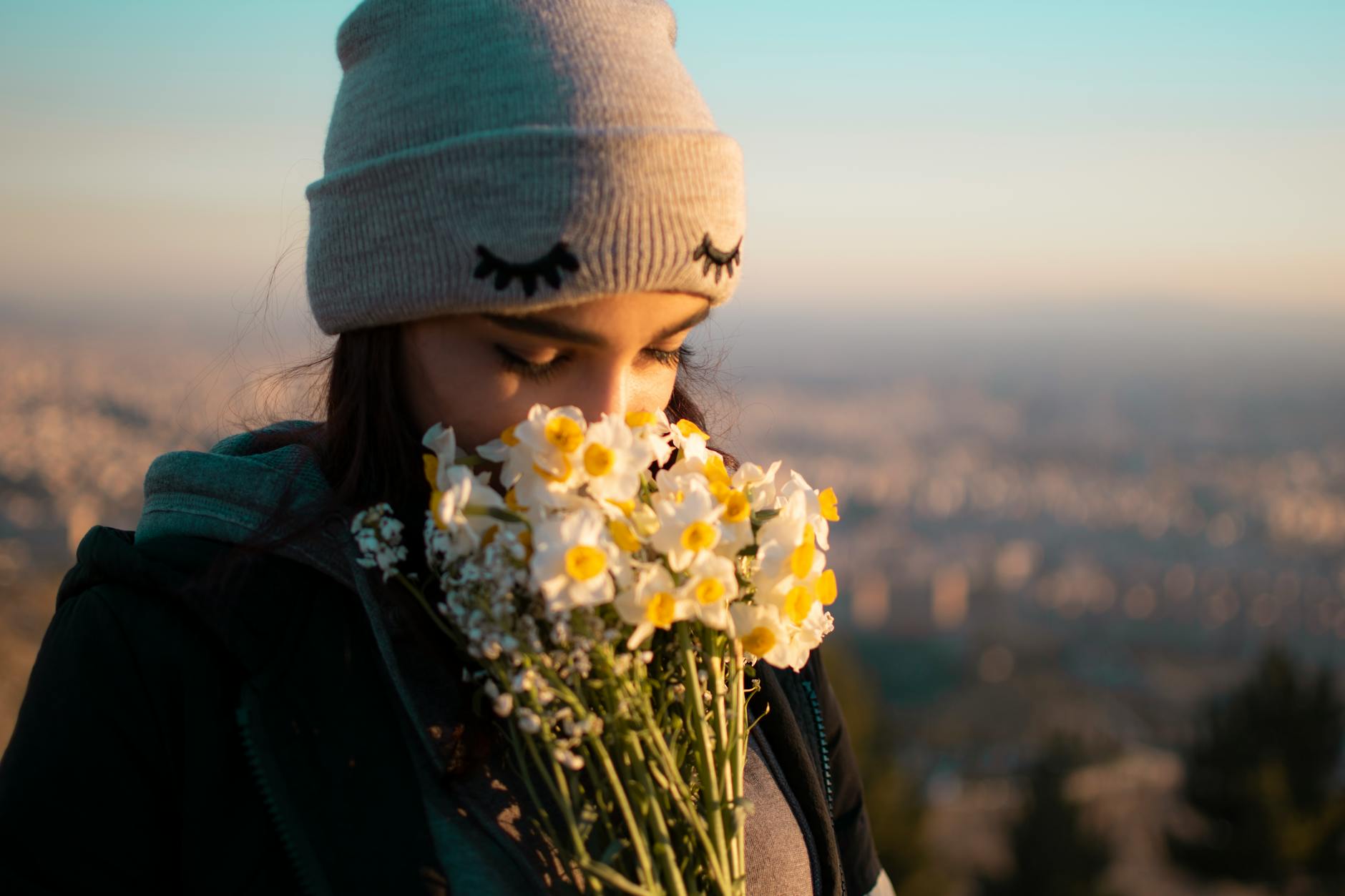A peaceful moment of a woman with closed eyes, enjoying a bouquet of flowers overlooking Tehran. - spring allergies anxiety