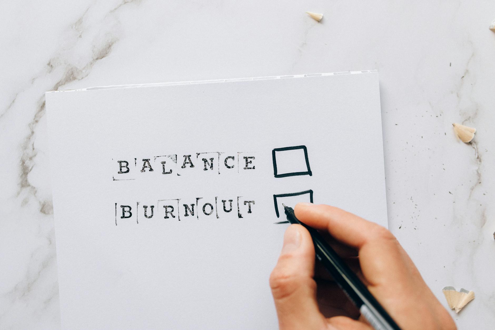 Close-up of a hand hovering over a checklist with options for balance or burnout, symbolizing stress and choice. - spring burnout recovery