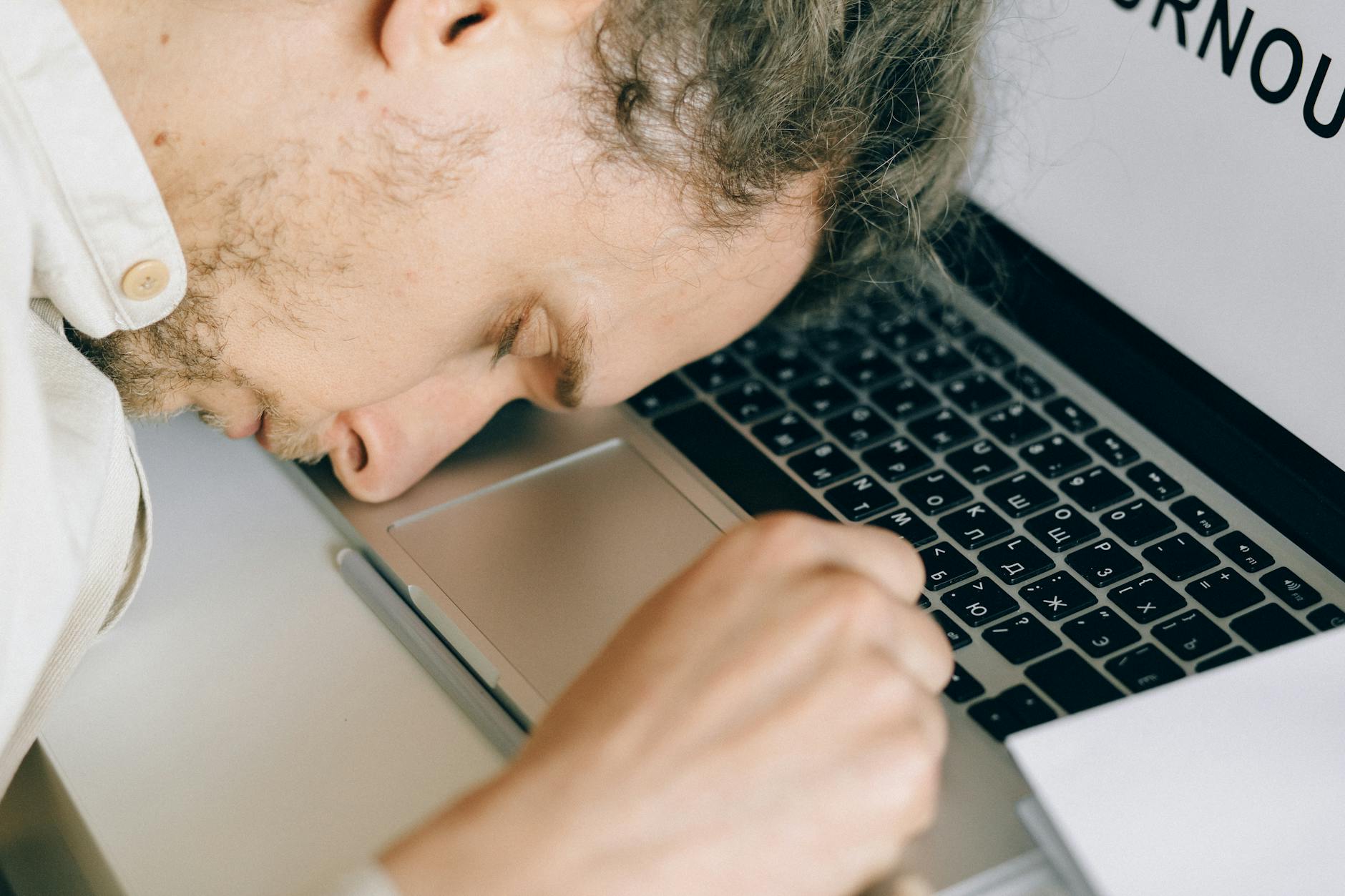 Exhausted employee resting head on laptop keyboard due to burnout and stress. - spring burnout recovery