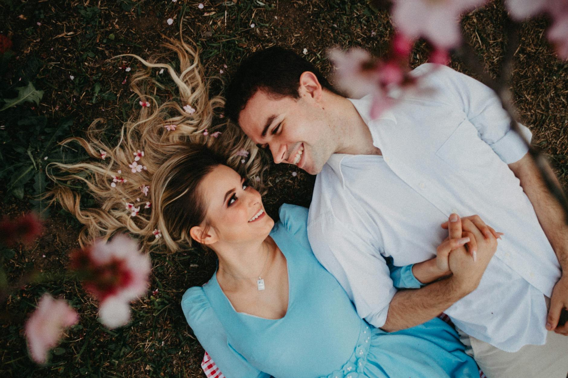 A joyous couple lying on the ground amid blooming flowers, symbolizing love and romance. - spring dating ideas