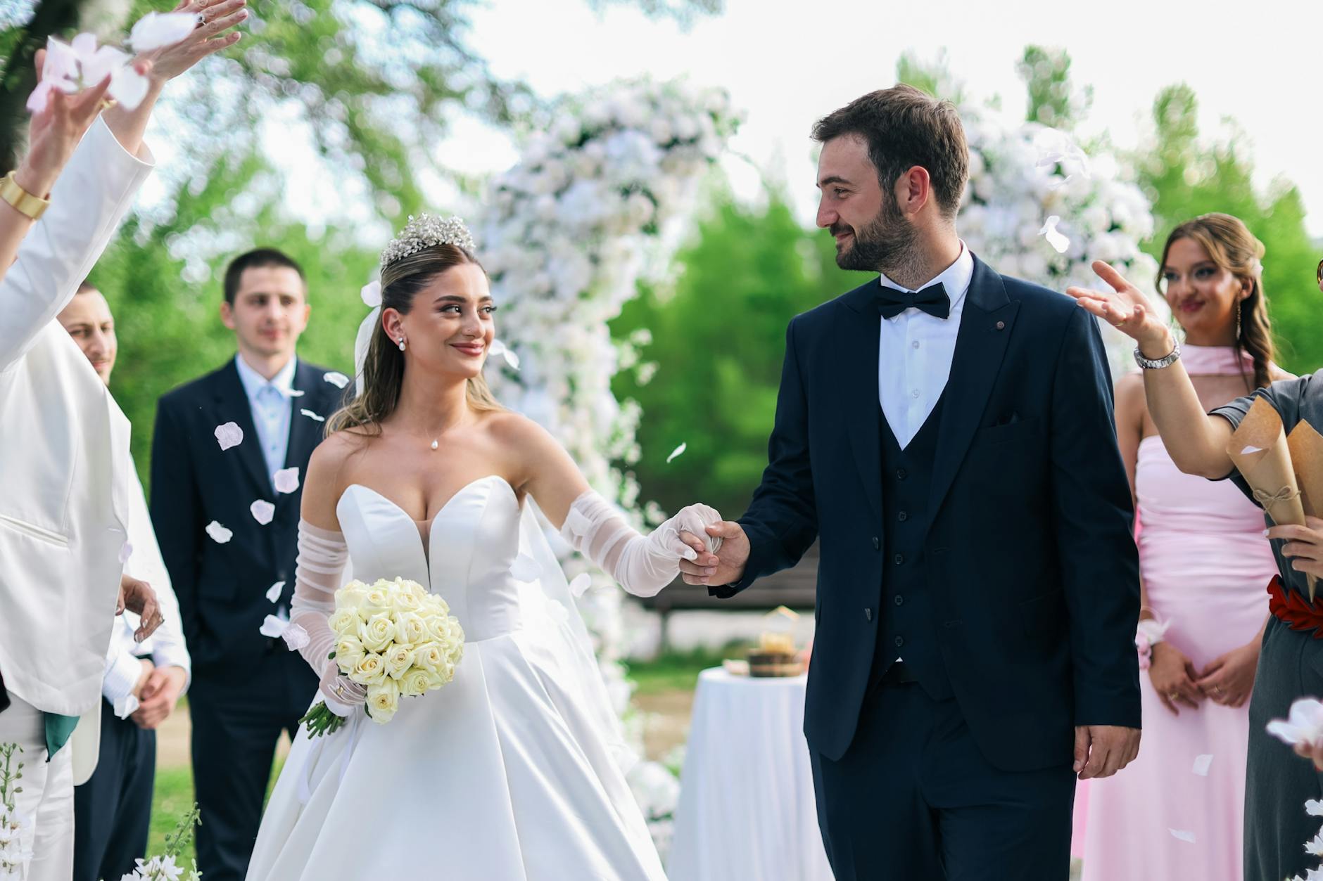 A joyful wedding ceremony featuring a newlywed couple walking hand in hand outdoors. - spring marriage joy