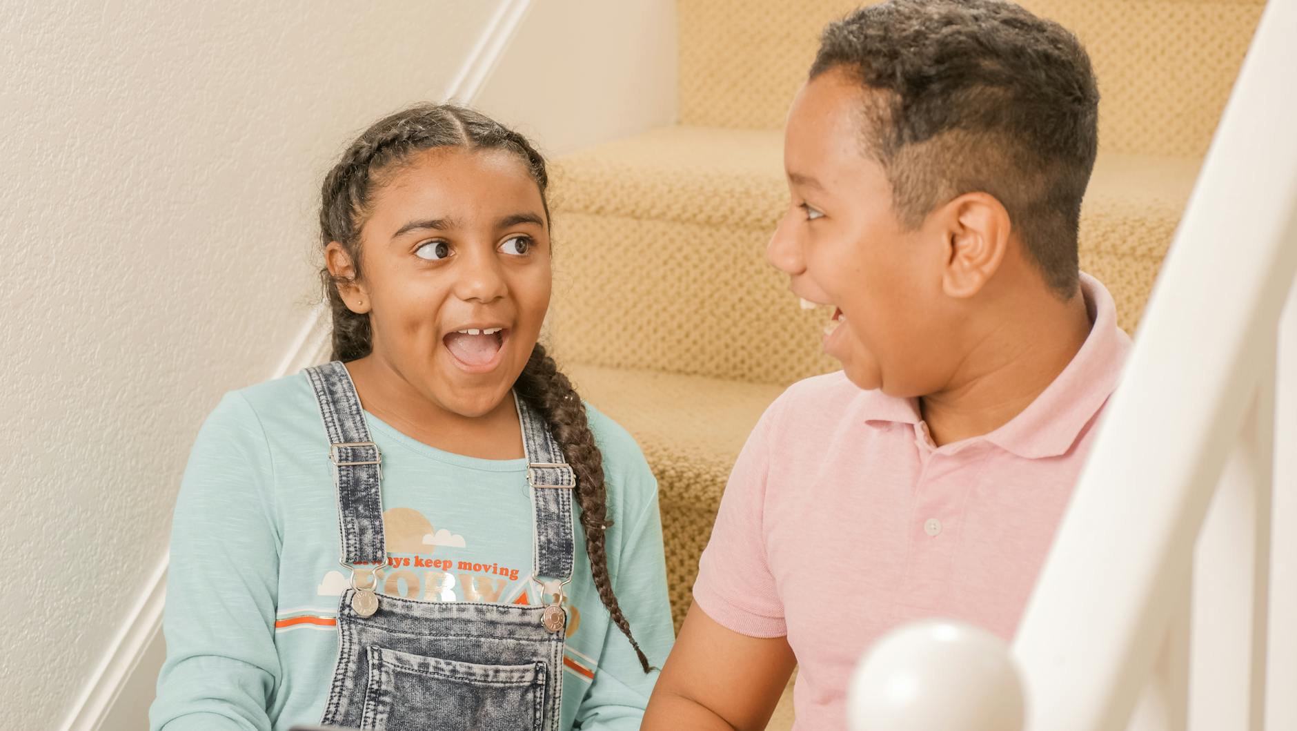 Happy siblings sharing a joyful moment on the staircase indoors. - step sibling rivalry