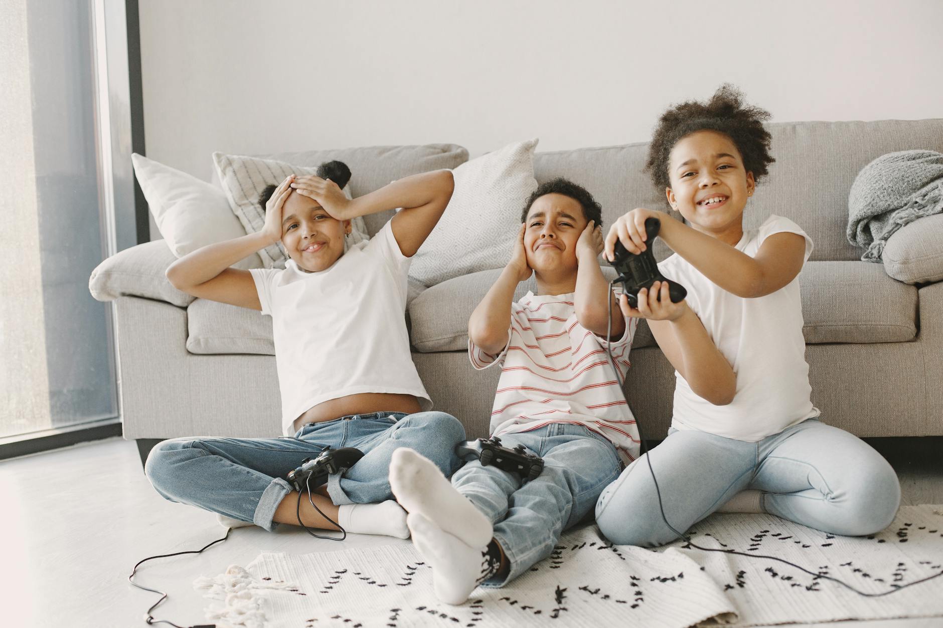 Three kids having fun playing video games on the living room floor. - step sibling rivalry