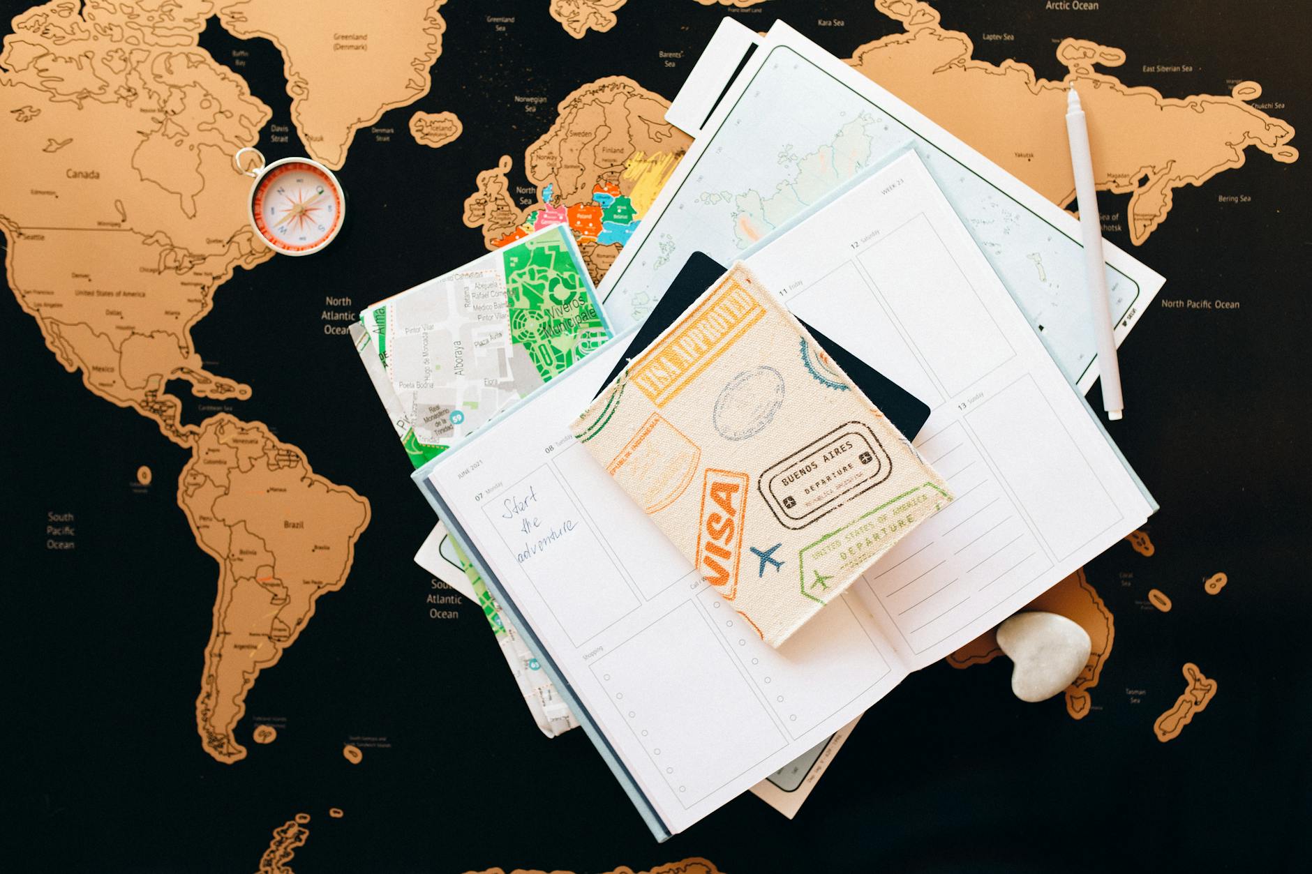 A flat lay of travel planning items on a map, featuring a compass, notebook, and guide for wanderlust enthusiasts. - summer vacation planning