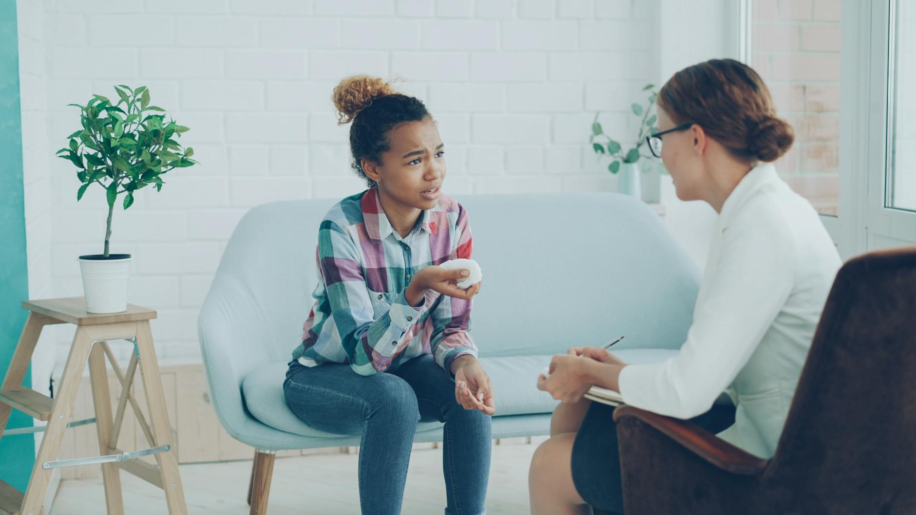 A young woman in discussion with a counselor during a session. Modern, bright office setting. - therapy tools growth