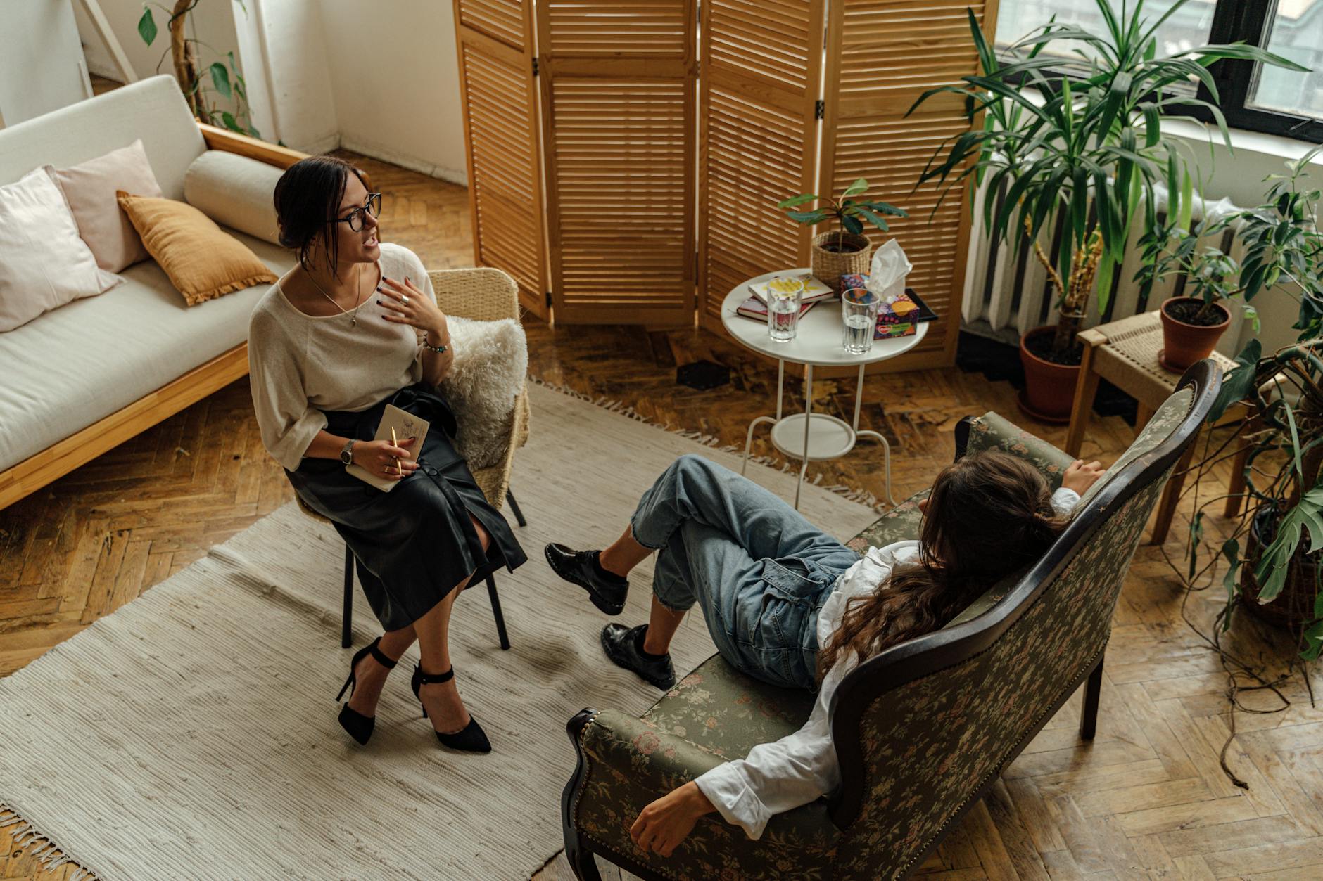 Two women engaged in a psychotherapy session in a warm, inviting interior with plants and natural lighting. - therapy tools growth