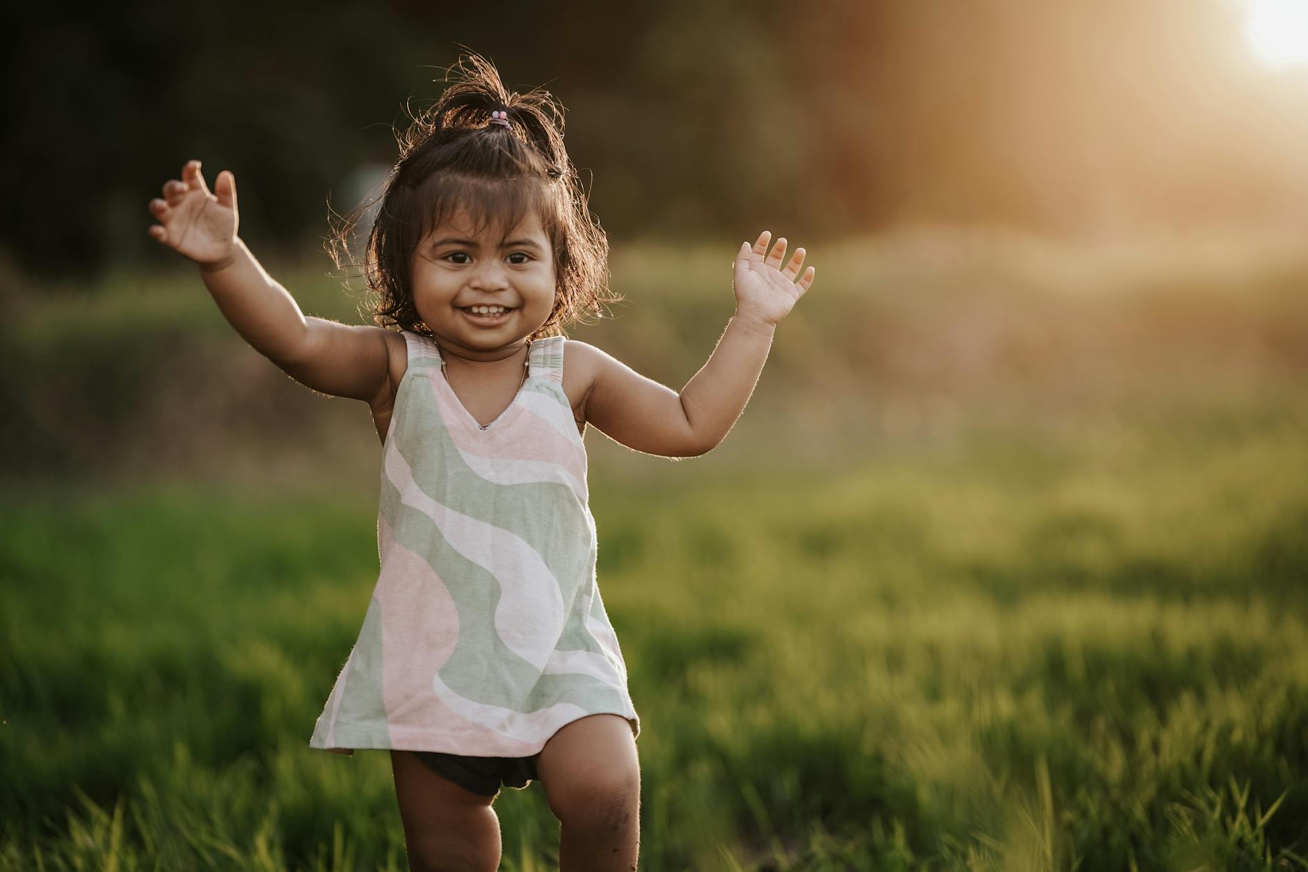 A happy child in a colorful dress enjoying playtime in a sunlit field. Outdoor fun and carefree joy. - toddler energy bursts