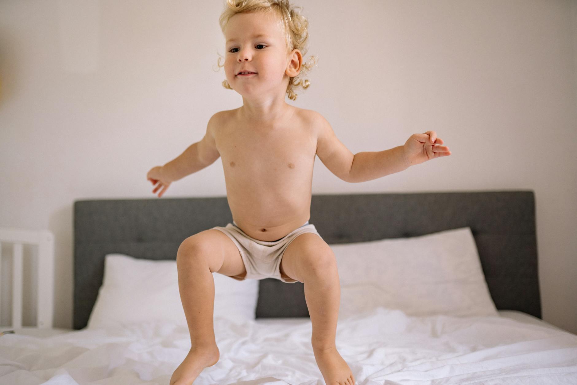 A cheerful child jumping on a bed, capturing the essence of playful moments indoors. - toddler energy bursts