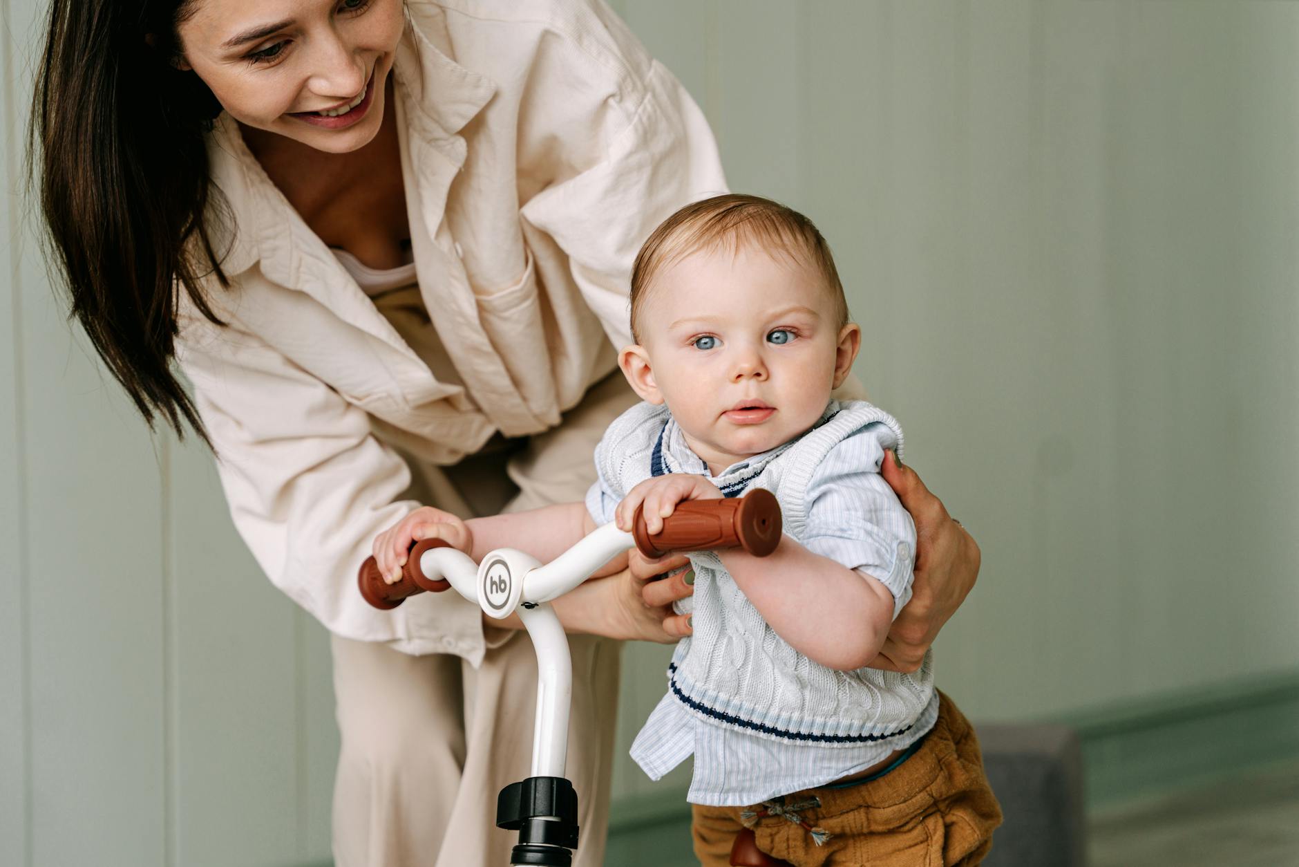 A joyful moment between a mother and her baby indoors, engaging in a playful biking activity. - toddler growth spurts