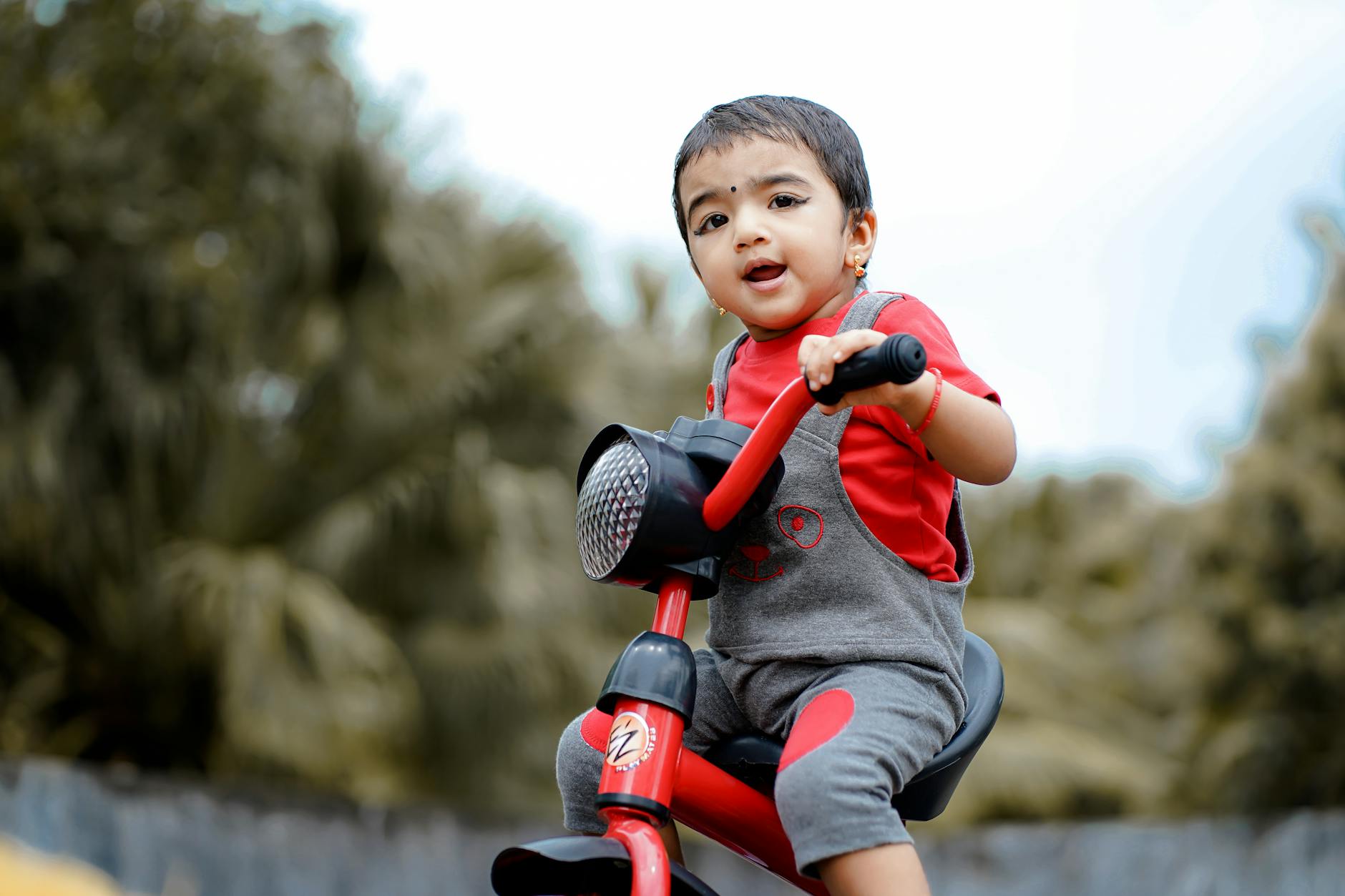 Cute child enjoying a ride on a tricycle in a lush outdoor setting, showcasing joy and innocence. - toddler outdoor activities