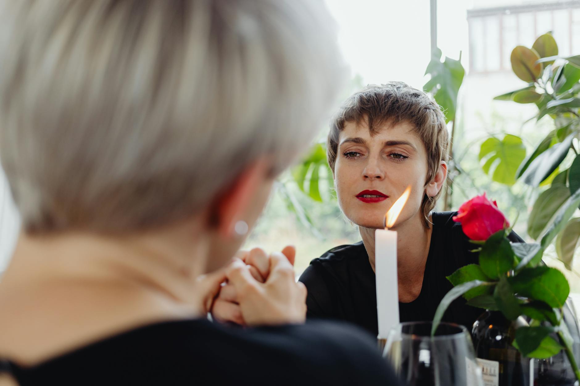 A loving lesbian couple enjoying a romantic candlelit dinner with red roses. - vulnerable dating
