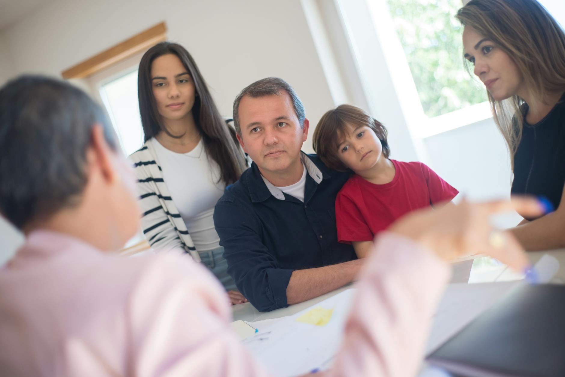 A family of four seeks advice from a professional during an indoor consultation in a bright room. - active listening family