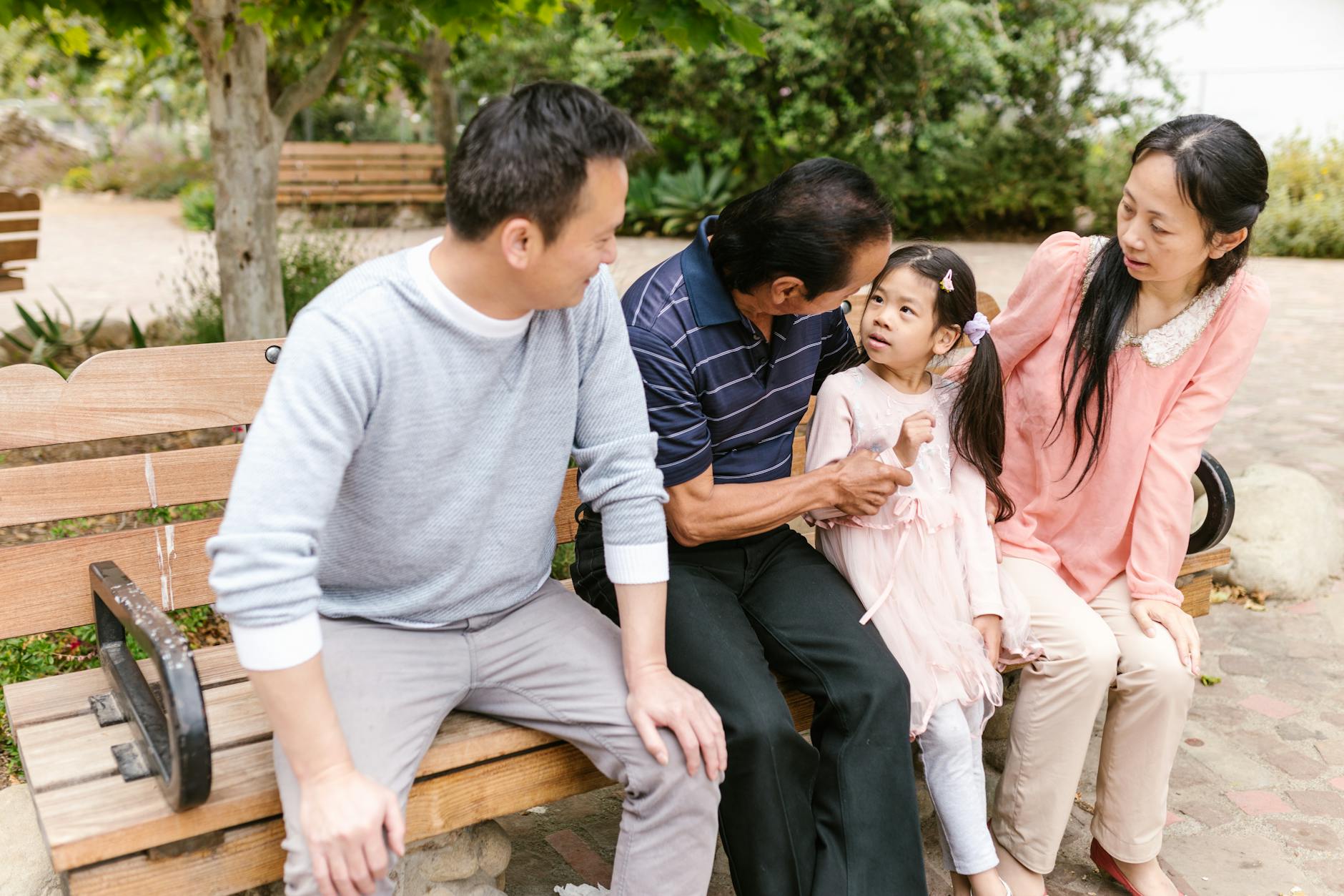Asian family sitting on a park bench, sharing laughter and bonding moments together. - active listening family