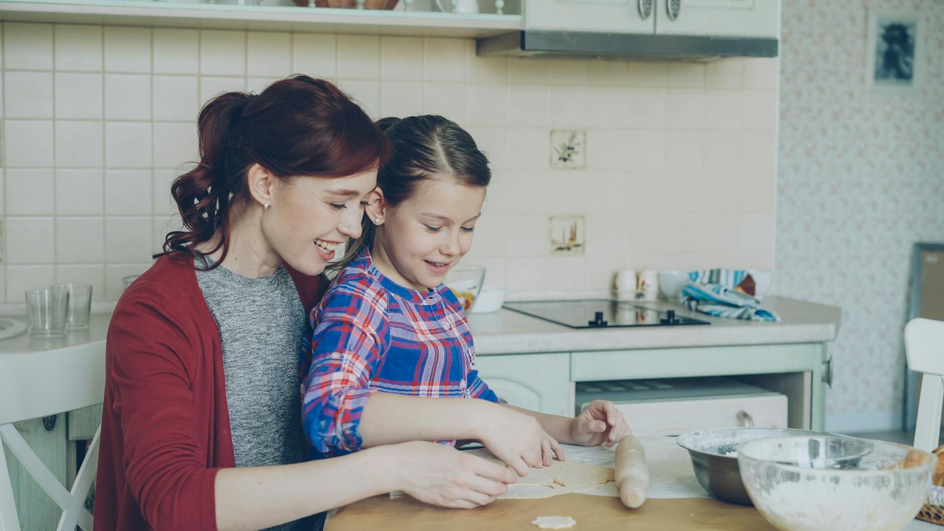 A mother and daughter share a joyful time baking together in a cozy kitchen. - blended family summer