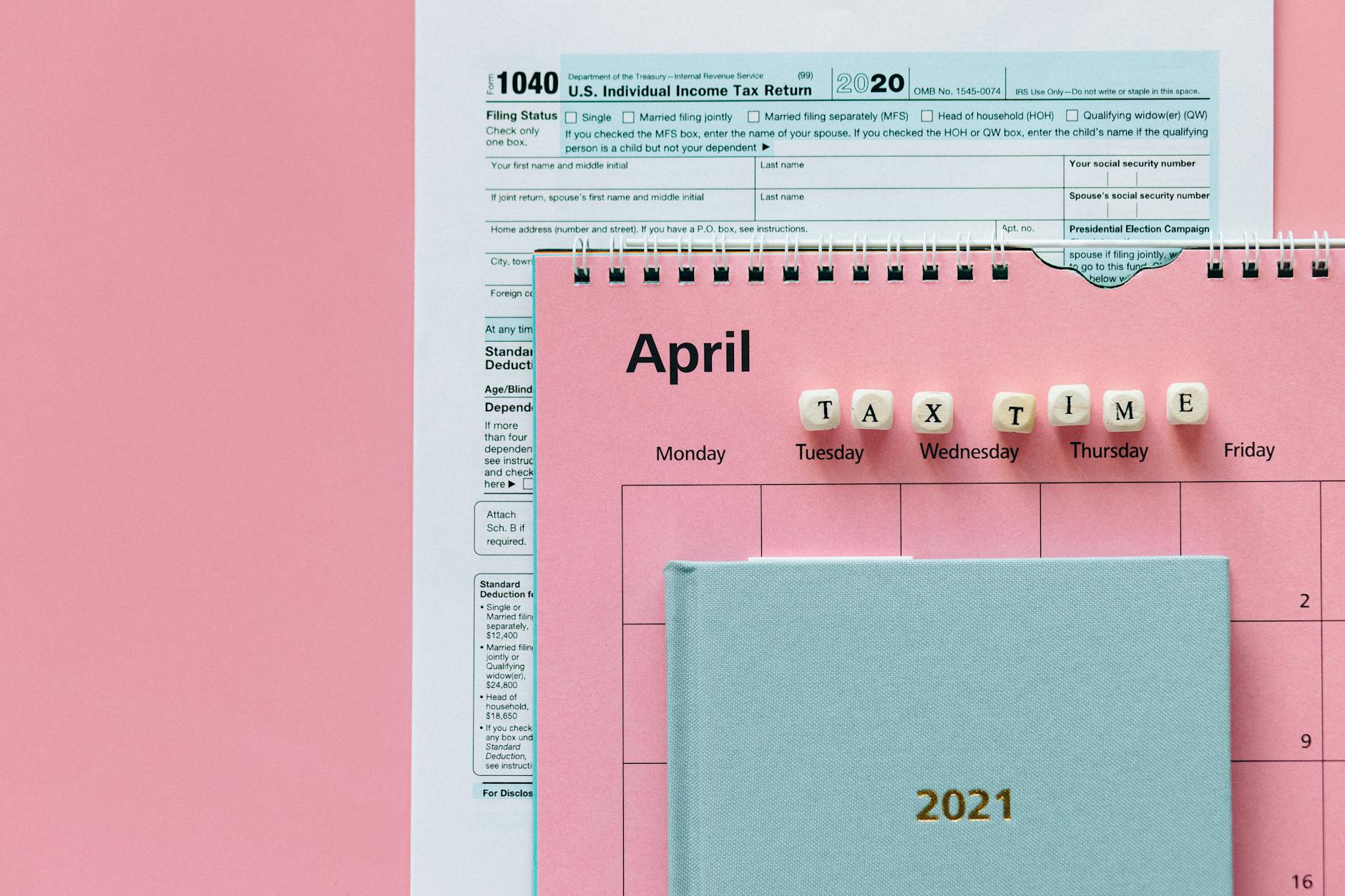 Flat lay image of tax forms, calendar, and 'tax time' reminder on a pink background. - budget spring dates