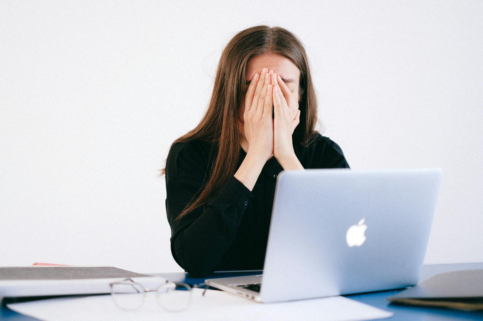 Woman feeling stressed and overwhelmed at her desk while working remotely on a laptop. - cbt for spring stress