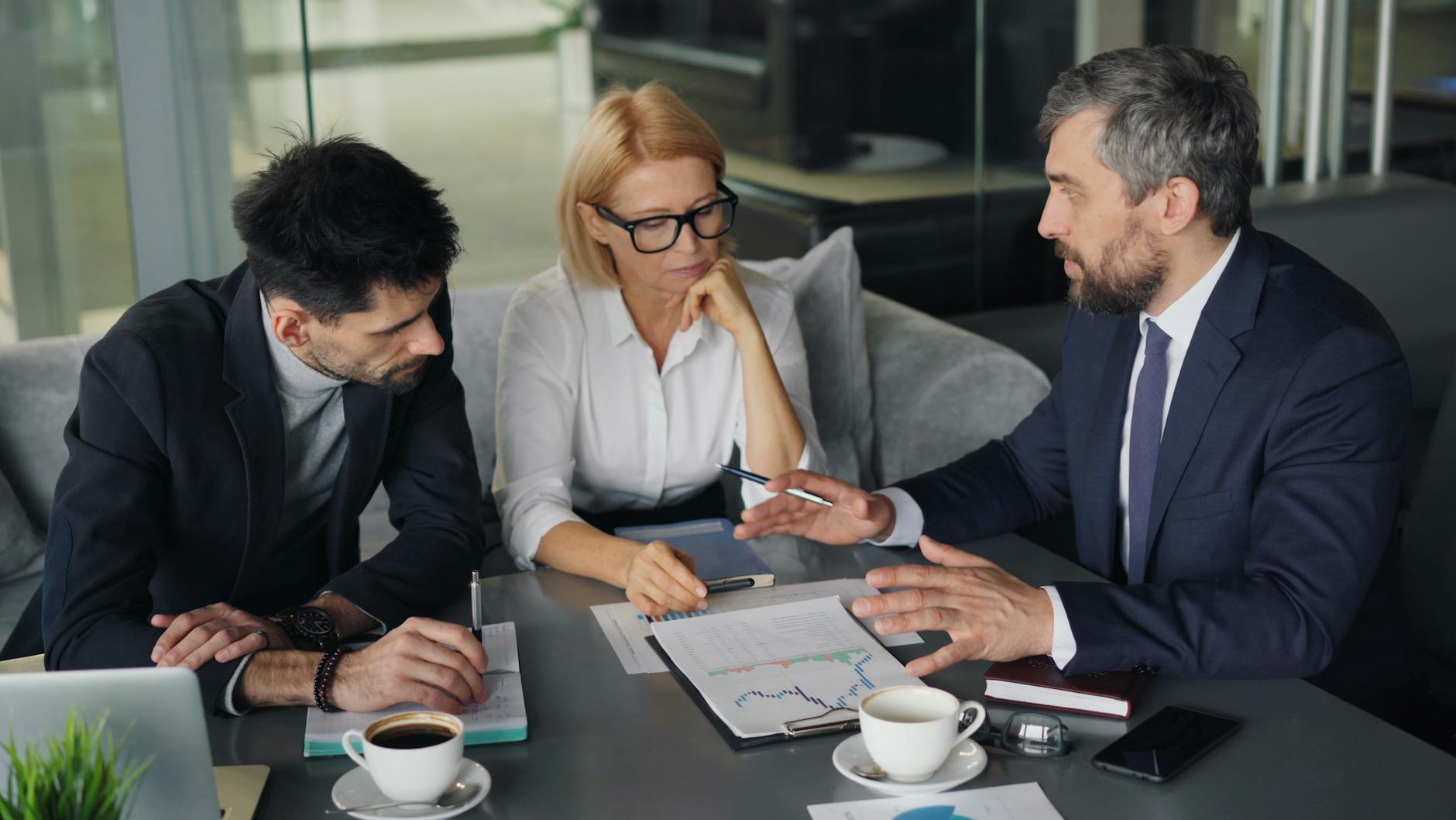Professional colleagues engaged in a business meeting discussing strategy over coffee. - coparenting communication strategies