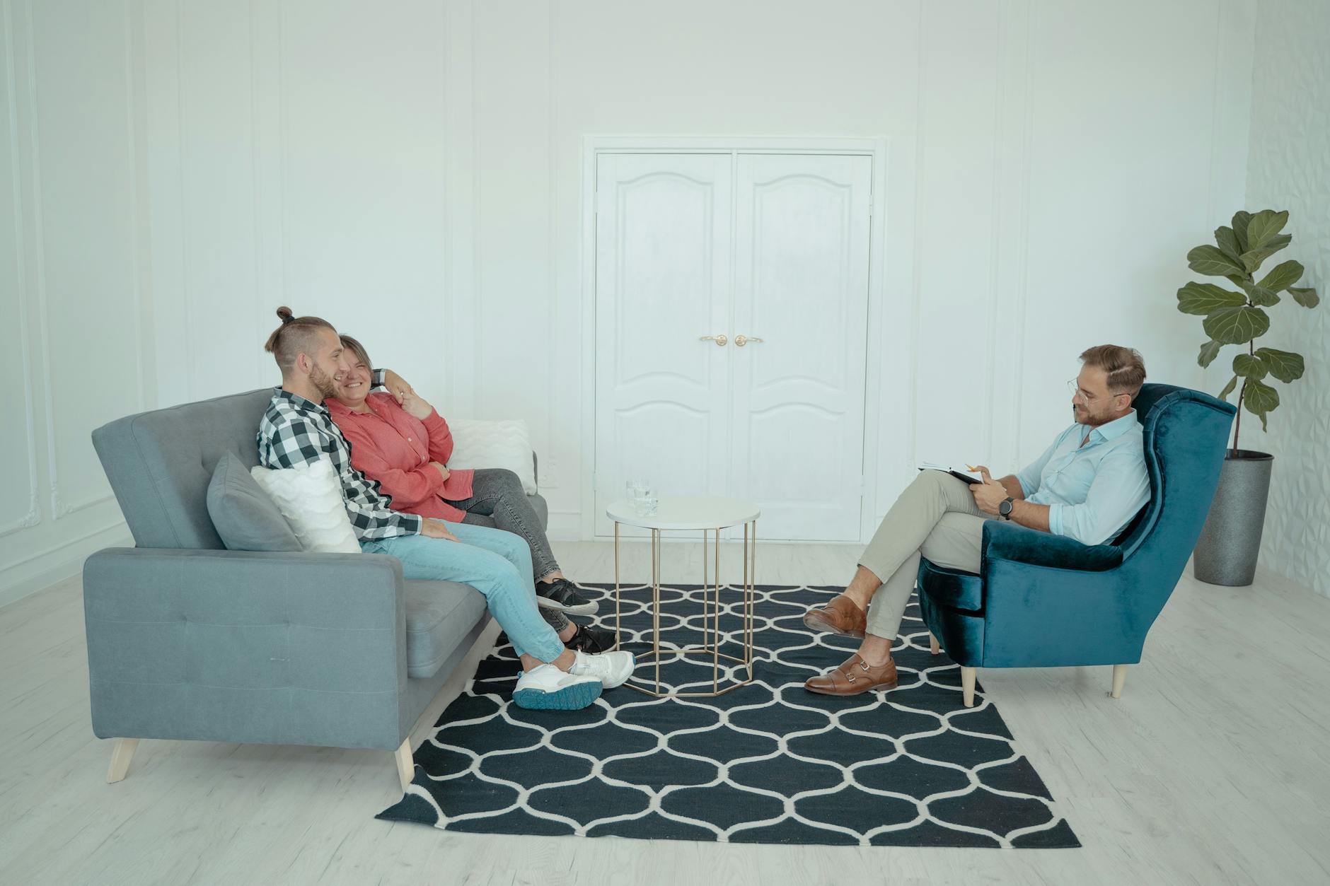 A married couple sits with a counselor discussing relationship issues in a modern office setting. - couples therapy goals