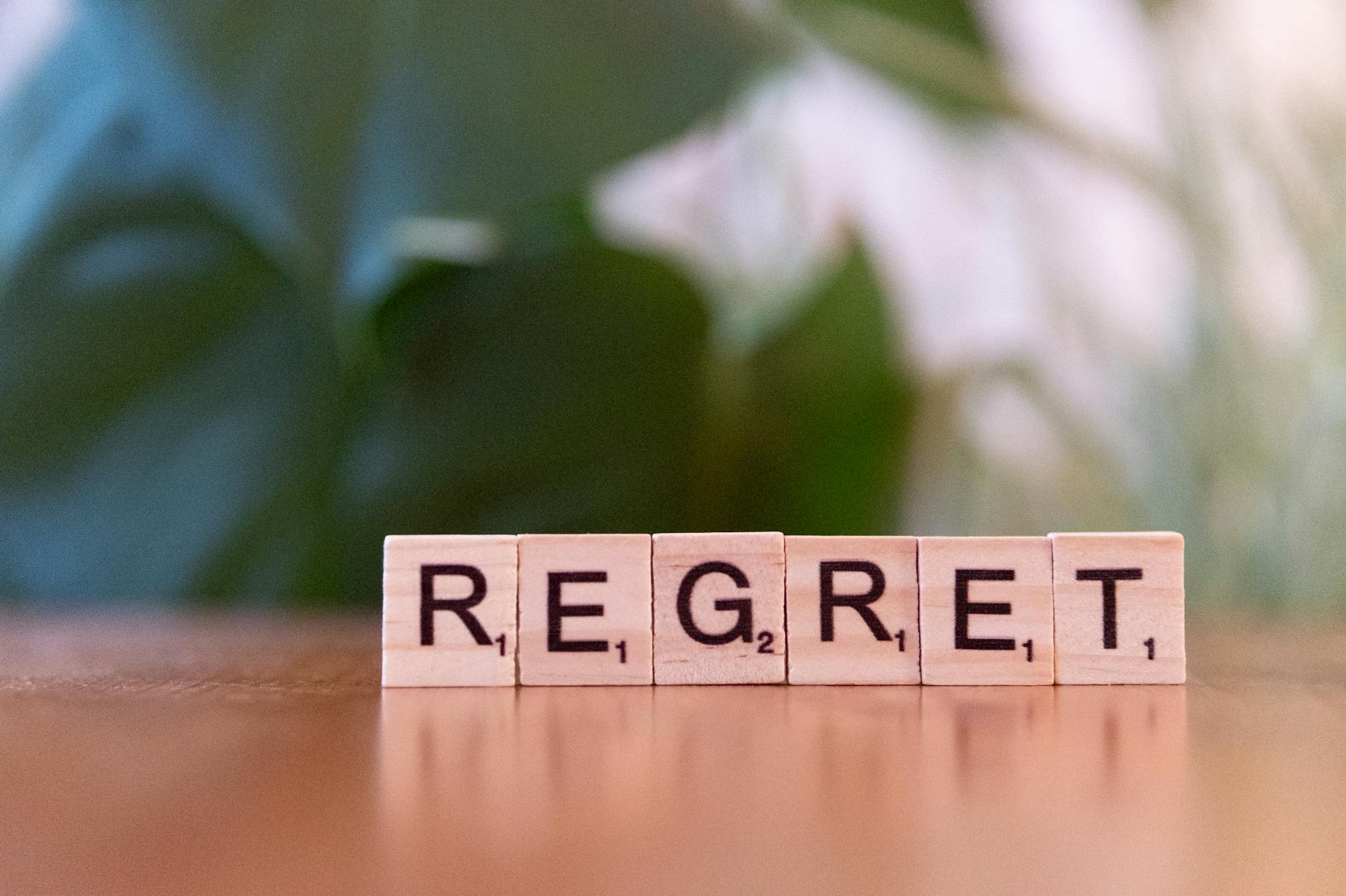 Wooden letter tiles forming the word 'Regret' on a blurred background, symbolizing emotions. - dbt emotional regulation