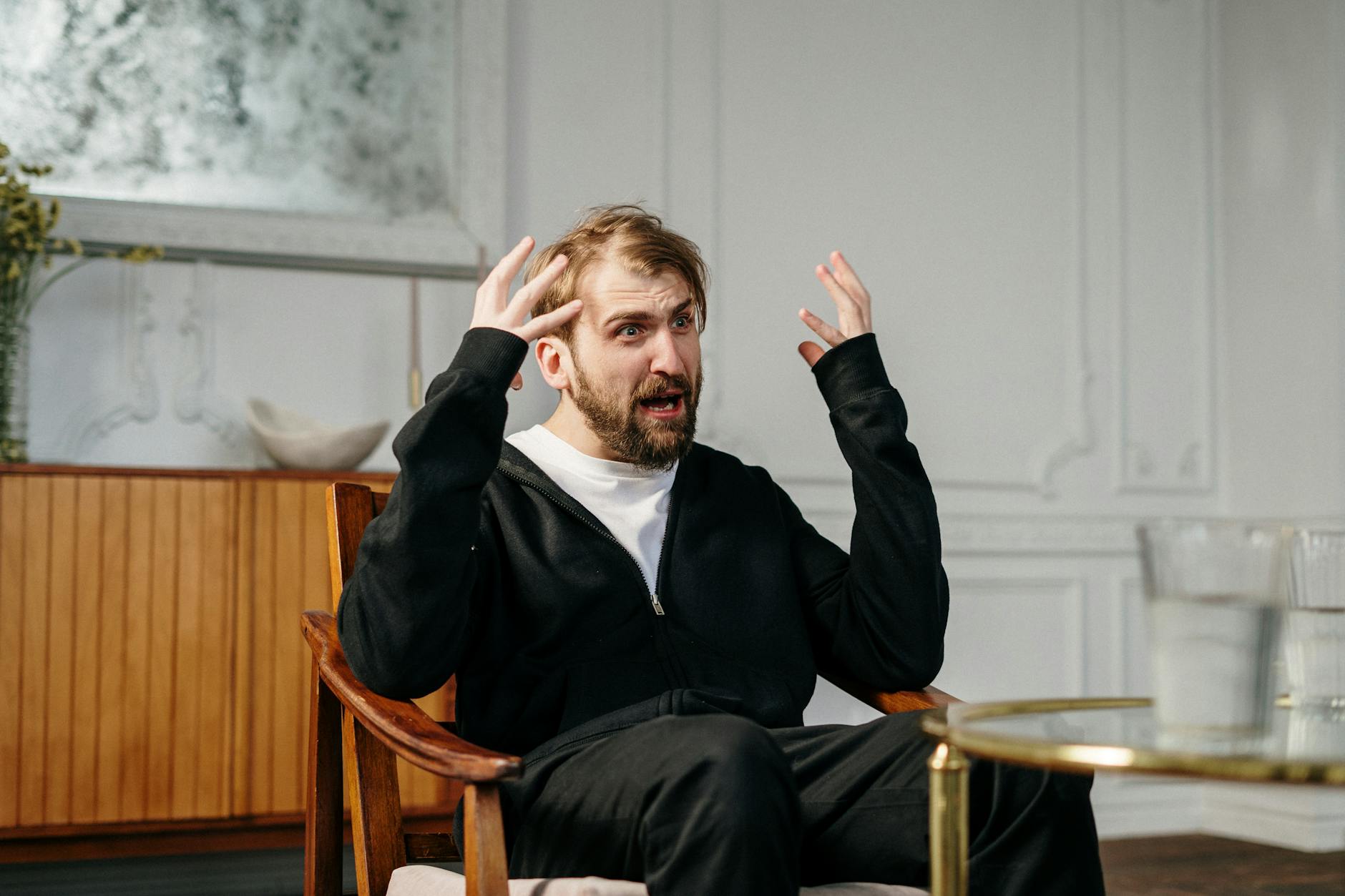 A man in a therapy session expressing emotions, seated indoors at a modern office. - dbt emotional regulation