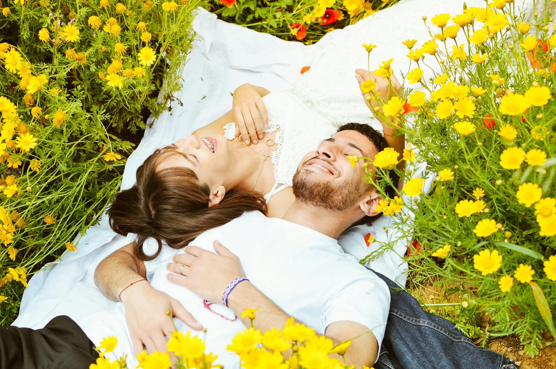 Couple lying in vibrant field of yellow flowers, capturing love and tranquility. - deepen relationship spring