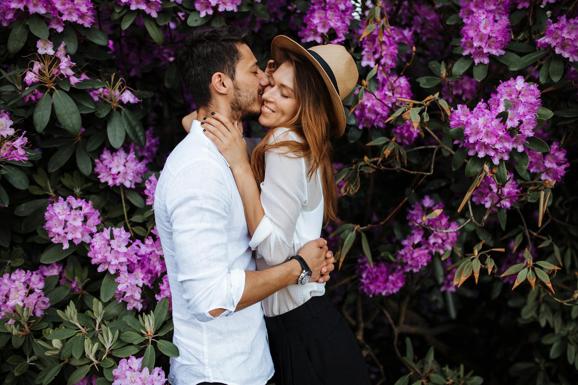 A couple sharing an intimate moment surrounded by vibrant purple rhododendron flowers. - deepen relationship spring