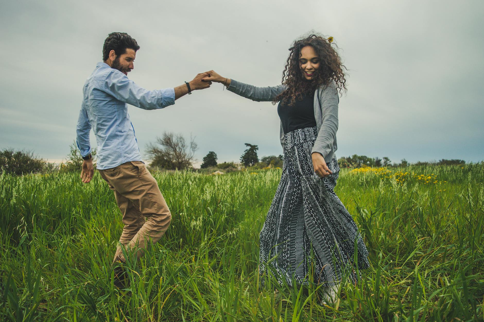 A happy couple dances freely in a lush green field, embodying love and joy. - deepen relationship spring