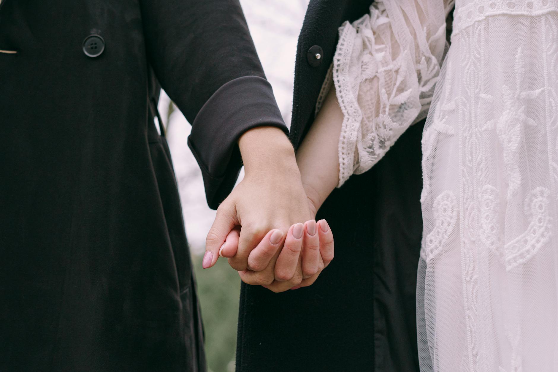 Close-up of two people holding hands, conveying love and togetherness outdoors. - early marriage connection