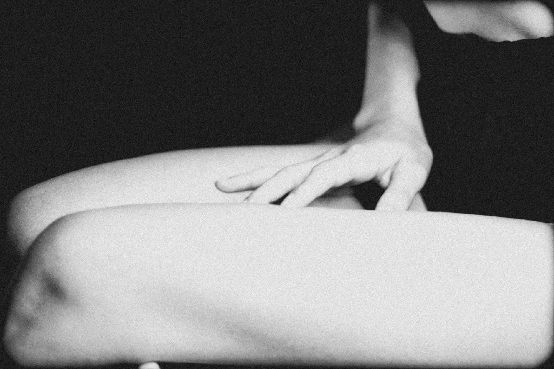 An artistic grayscale image of a hand gently touching a leg, emphasizing texture and mood. - emotional organization