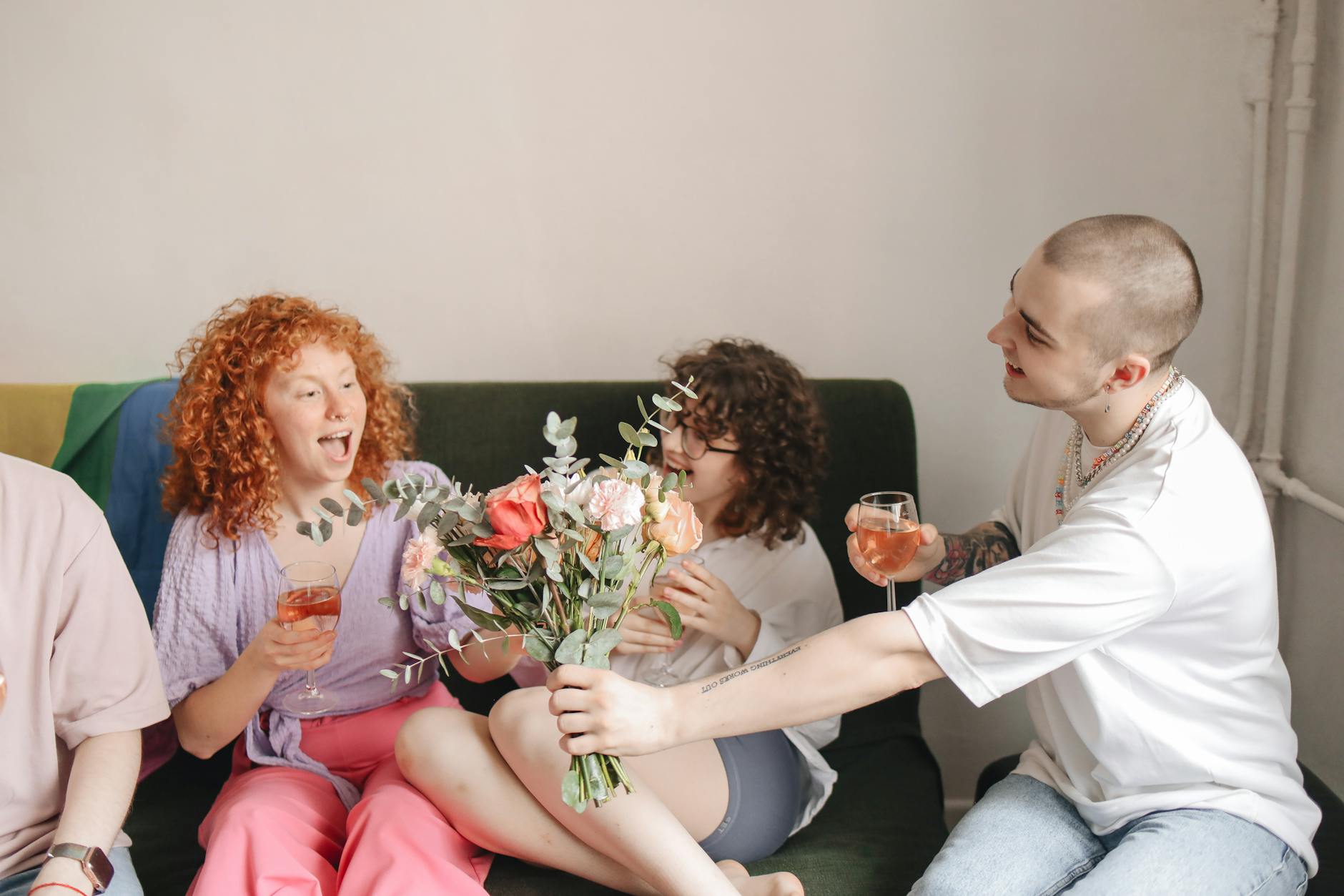 A group of friends enjoying a cheerful moment with flowers and drinks indoors. - friends to lovers