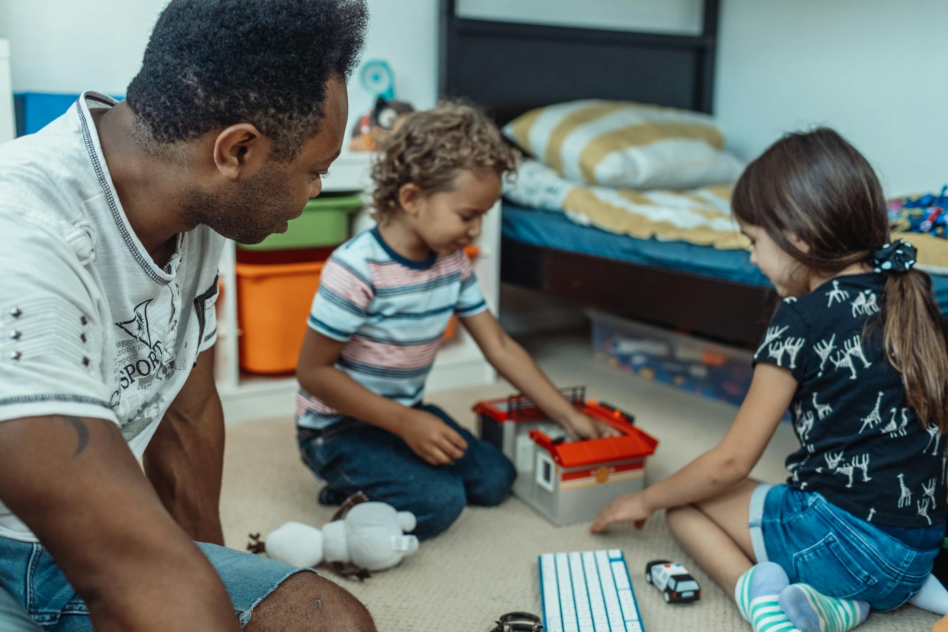A father and two children enjoying playtime together in a cozy bedroom setting. - kids cope change