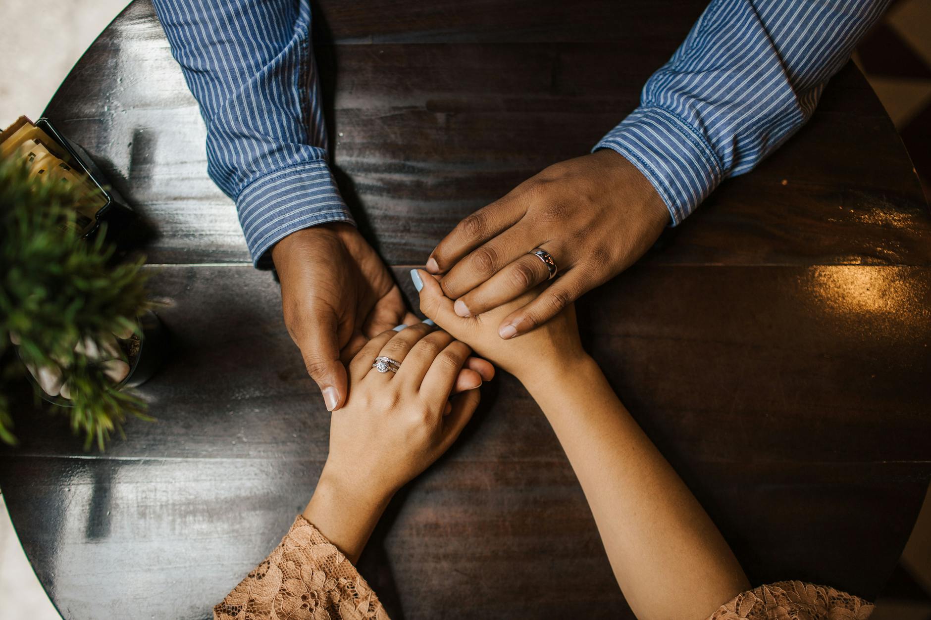 A couple holding hands on a wooden table, expressing love and connection. - marriage growth strategies