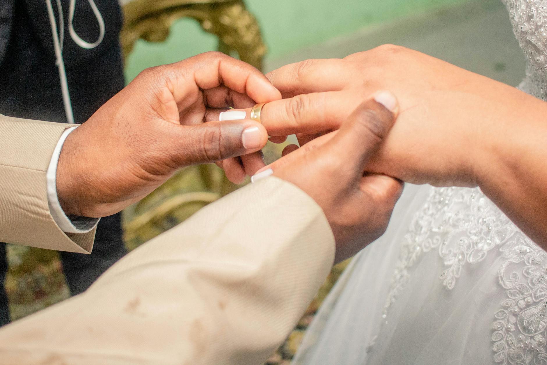 A close-up captures a groom placing a wedding ring on the bride's finger during their ceremony. - marriage growth strategies