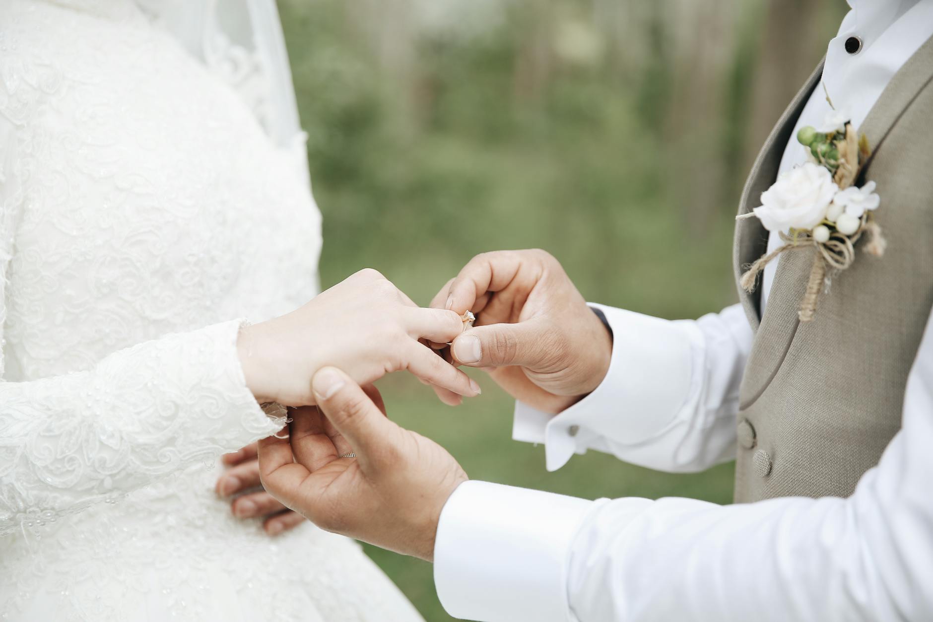 Close-up of a groom placing a wedding ring on the bride's finger during an outdoor ceremony. - marriage growth strategies