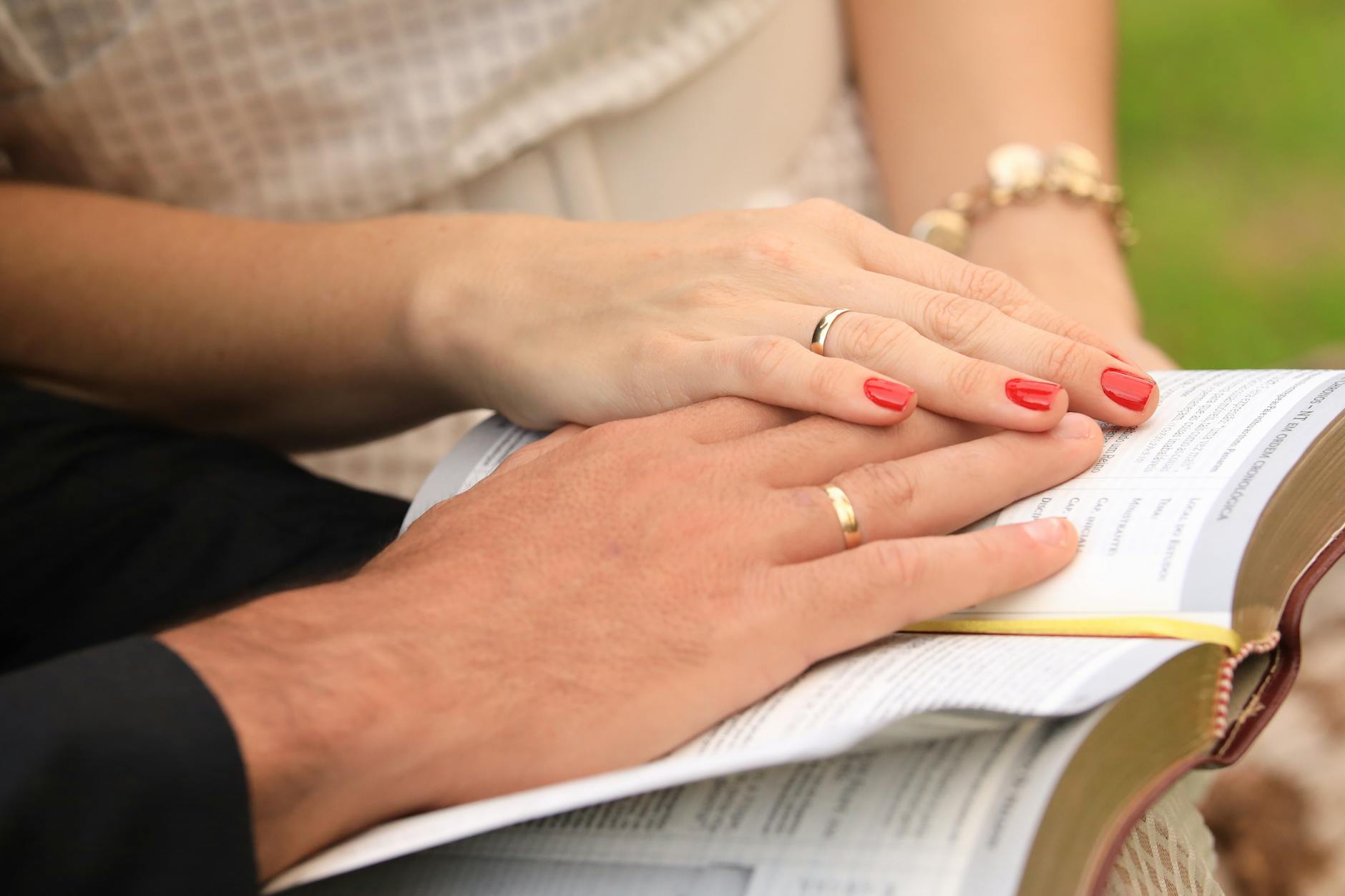 Close-up of a couple with wedding rings, hands resting on an open Bible, symbolizing love and faith. - marriage growth strategies