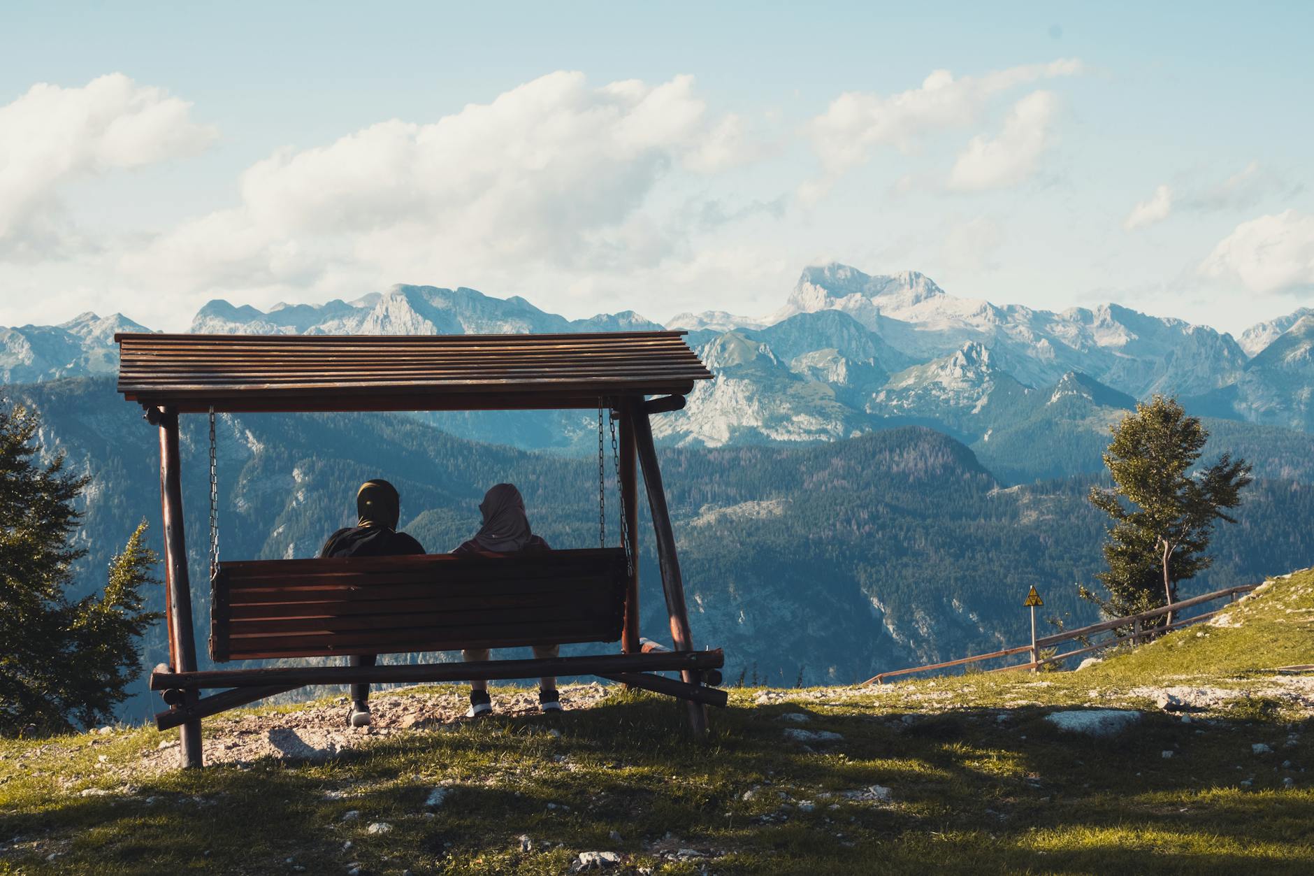 Two people enjoy a serene mountain view from a swing at Tolmin, Slovenia. - marriage plateau