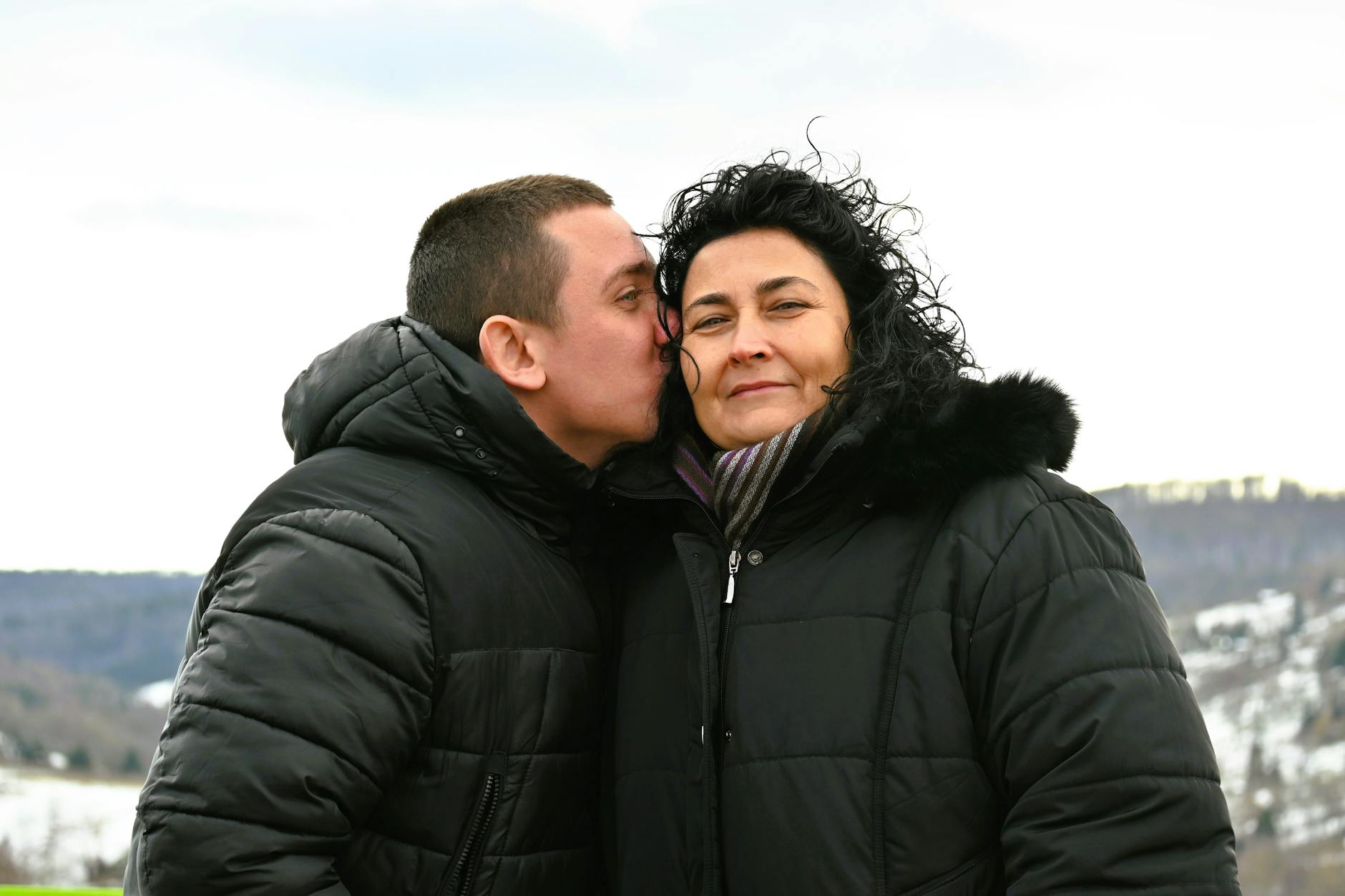 A heartwarming moment between a mother and son bundled up in winter coats outdoors. - marriage after winter