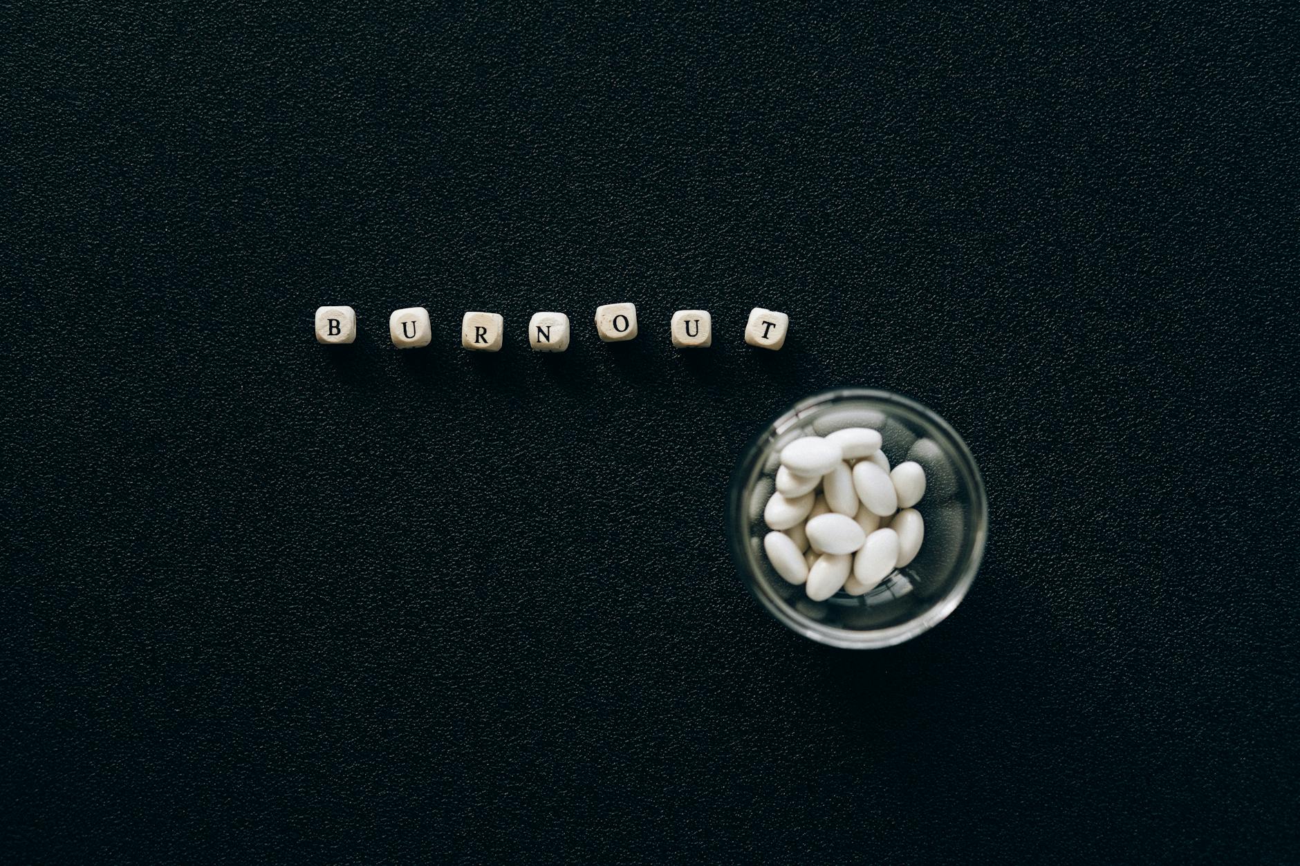 A conceptual image depicting burnout using pills and scrabble tiles on a black surface. - mental health reset