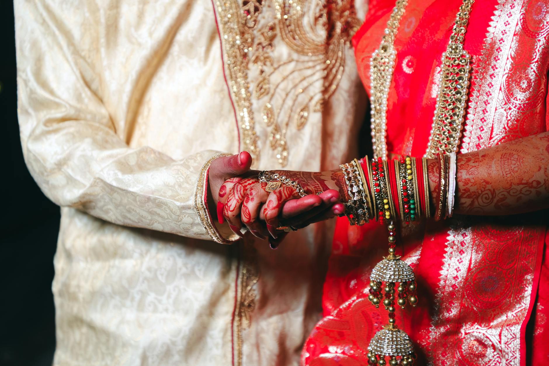 Beautiful Indian wedding close-up showcasing bride and groom's hands and traditional attire. - new marriage adjustments